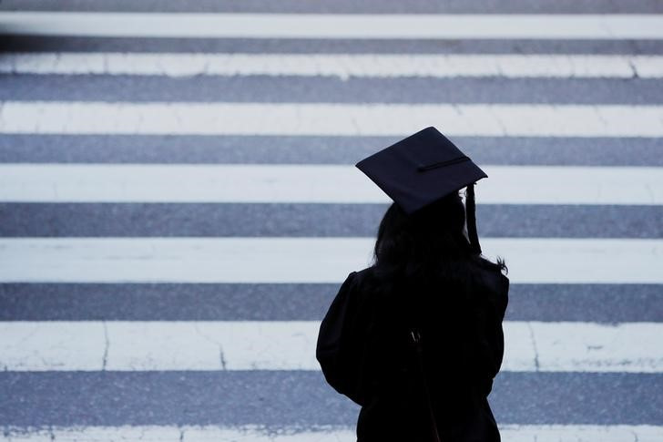 A graduating student waits to cross the street in Cambridge, Massachusetts