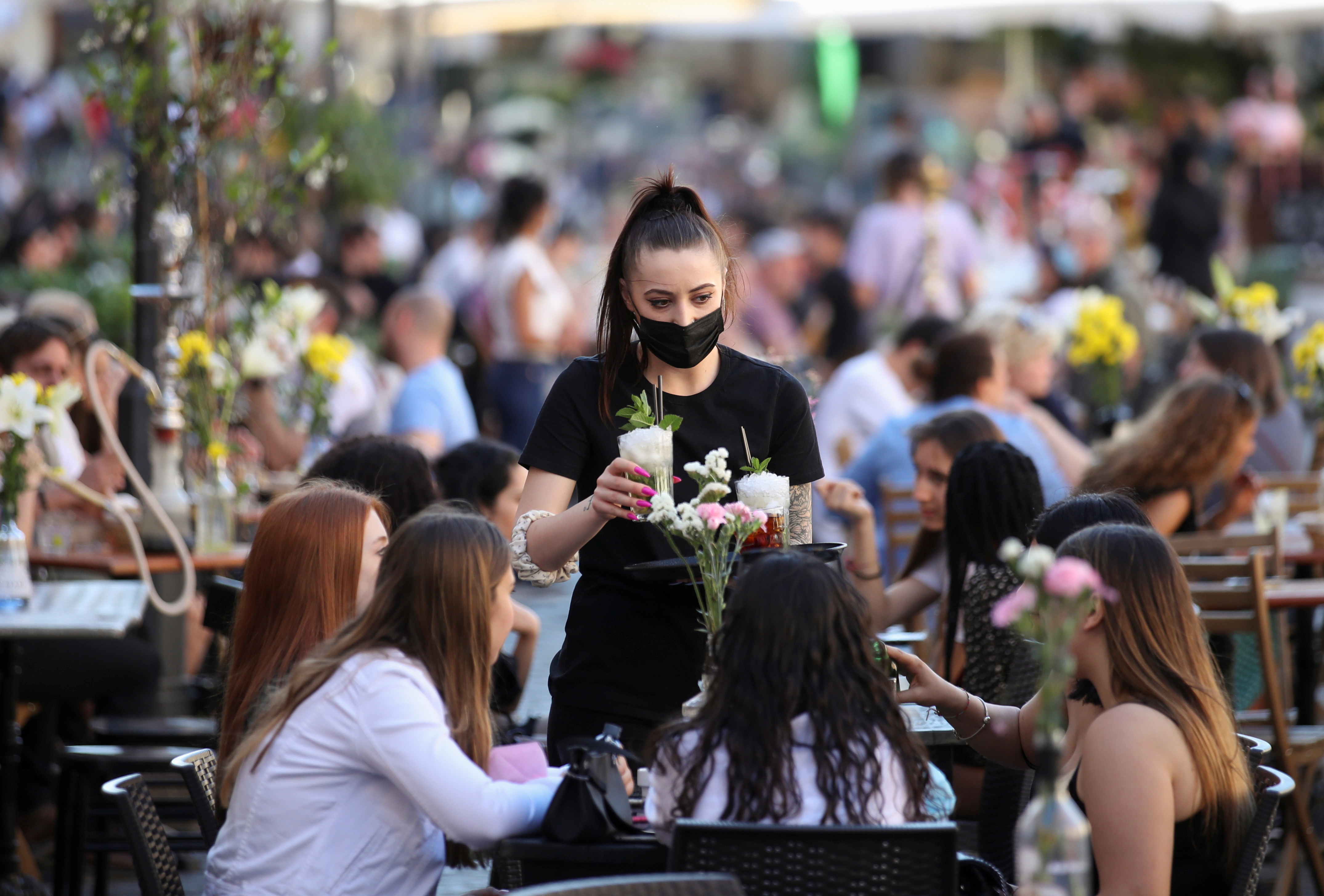 A waiter serves drinks to customers at a restaurant in Campo de' Fiori, in Rome
