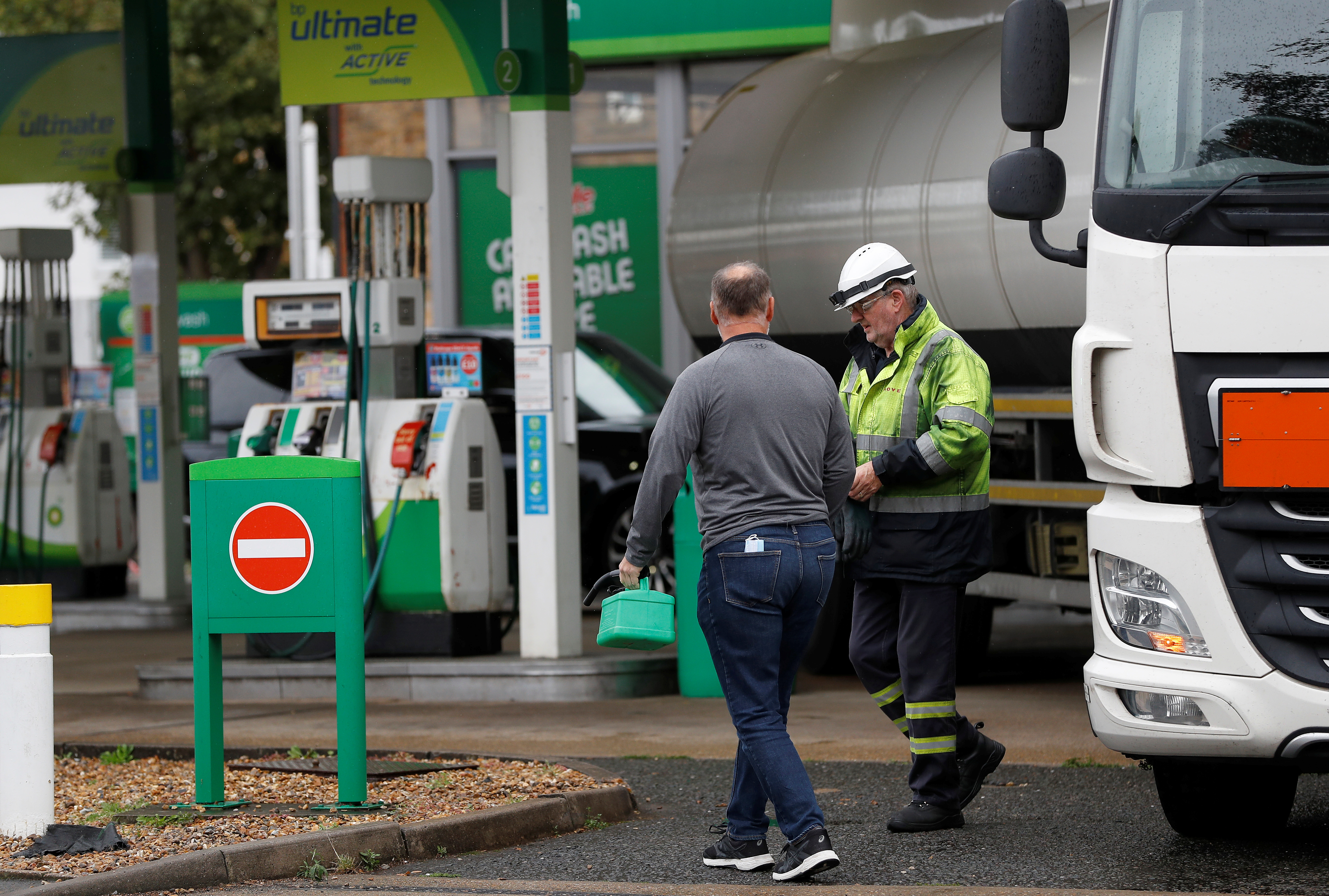 A tanker driver speaks with a customer at a BP filling station in Hersham, Britain, September 30, 2021. REUTERS/Peter Nicholls