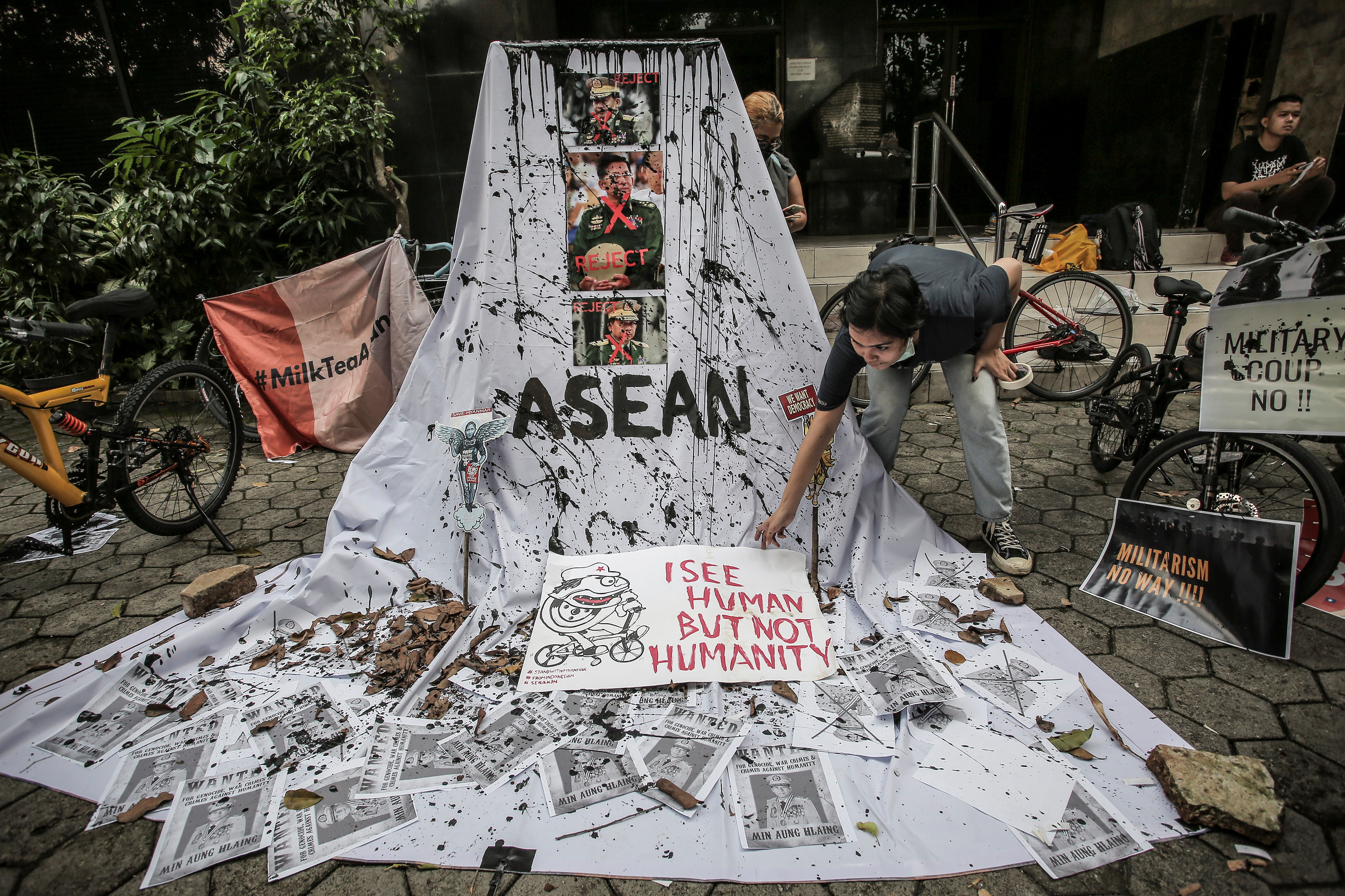 A woman prepares a placard out of crossed out portraits of Myanmar's junta chief Senior General Min Aung Hlaing during protest against the military coup in Myanmar, in Jakarta