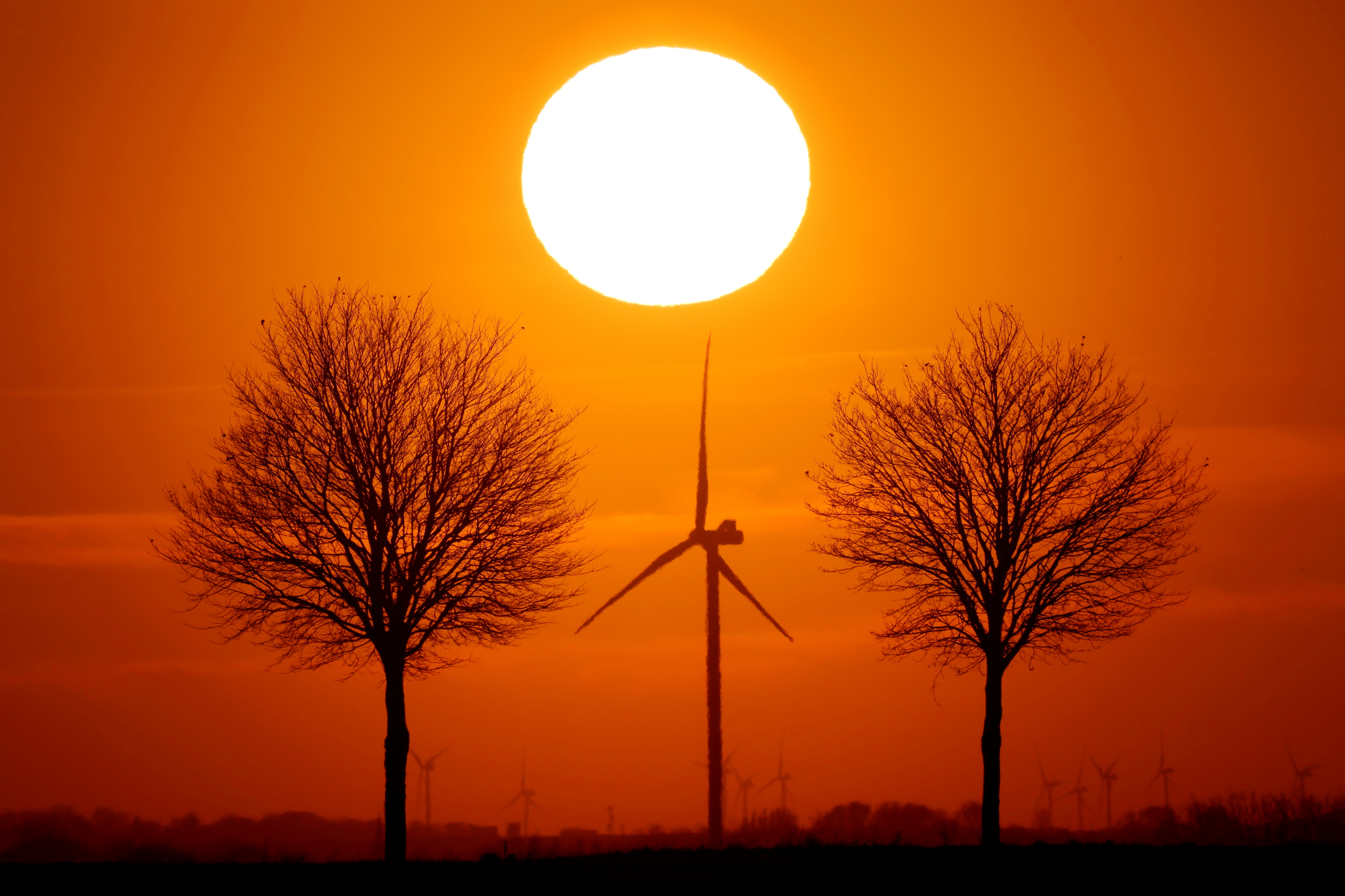 Power-generating windmill turbines are seen during sunset in Bourlon