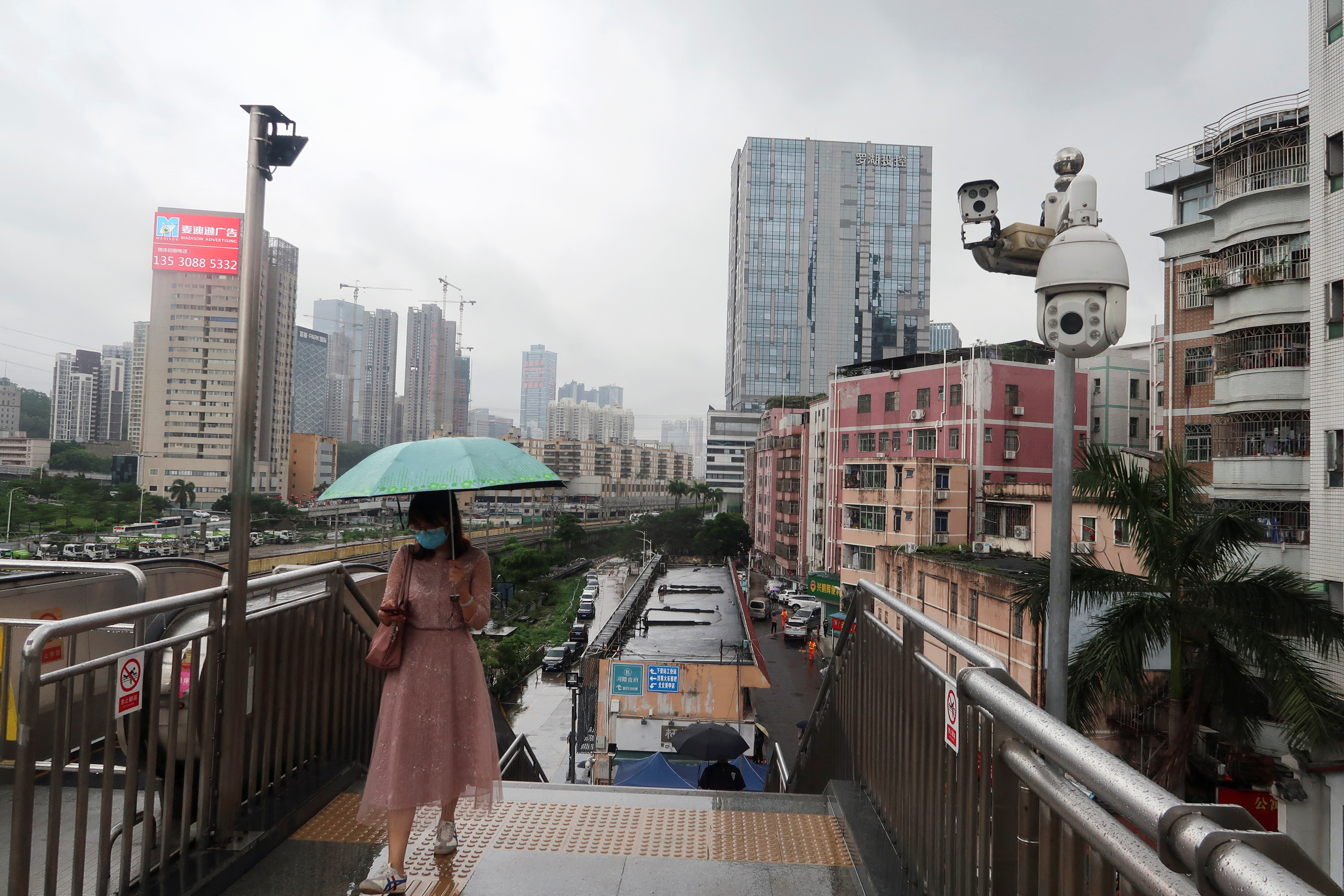 Woman walks past surveillance cameras near Caopu in Shenzhen
