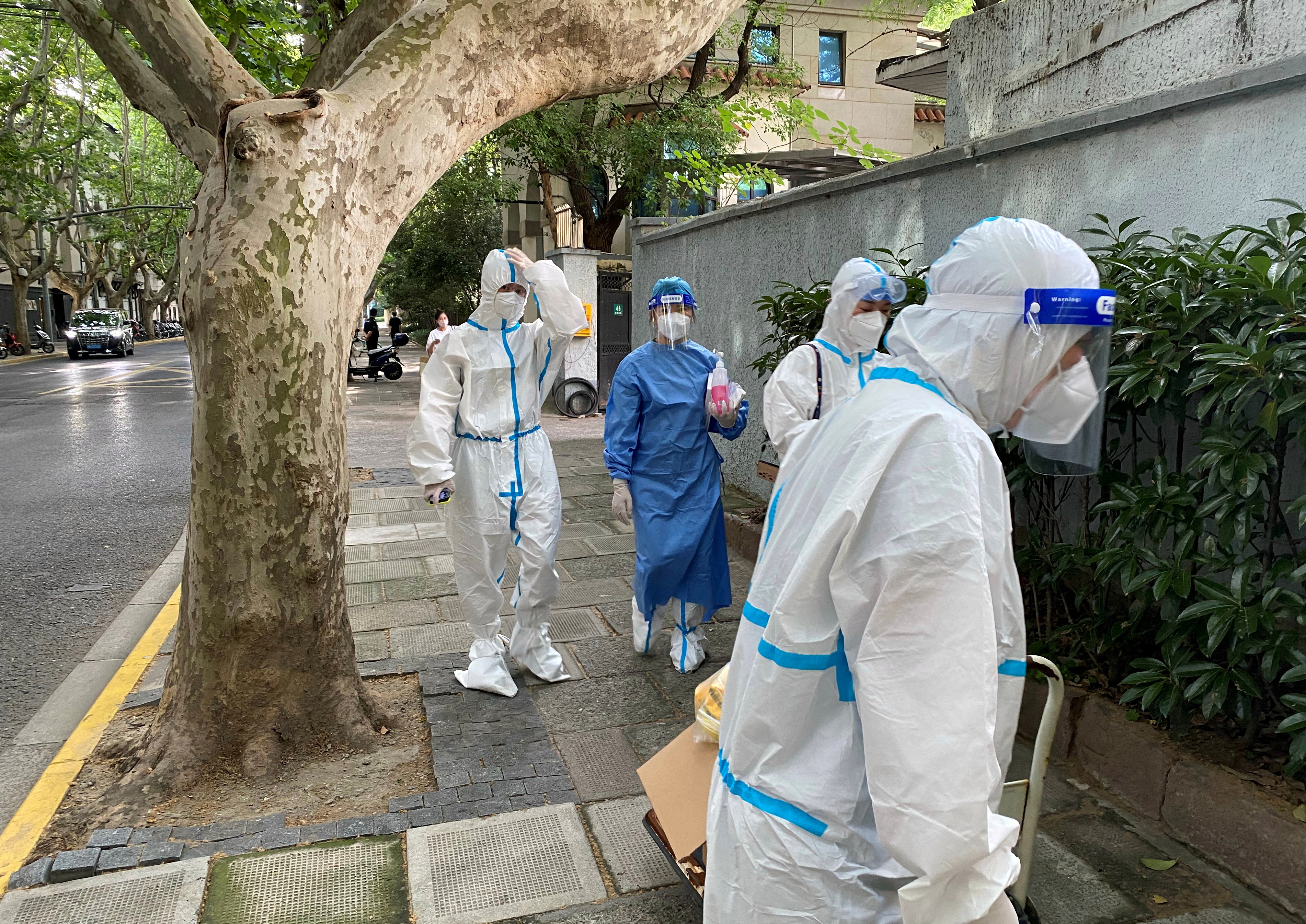 Workers in protective suits walk on a street, following the coronavirus disease (COVID-19) outbreak, in Shanghai
