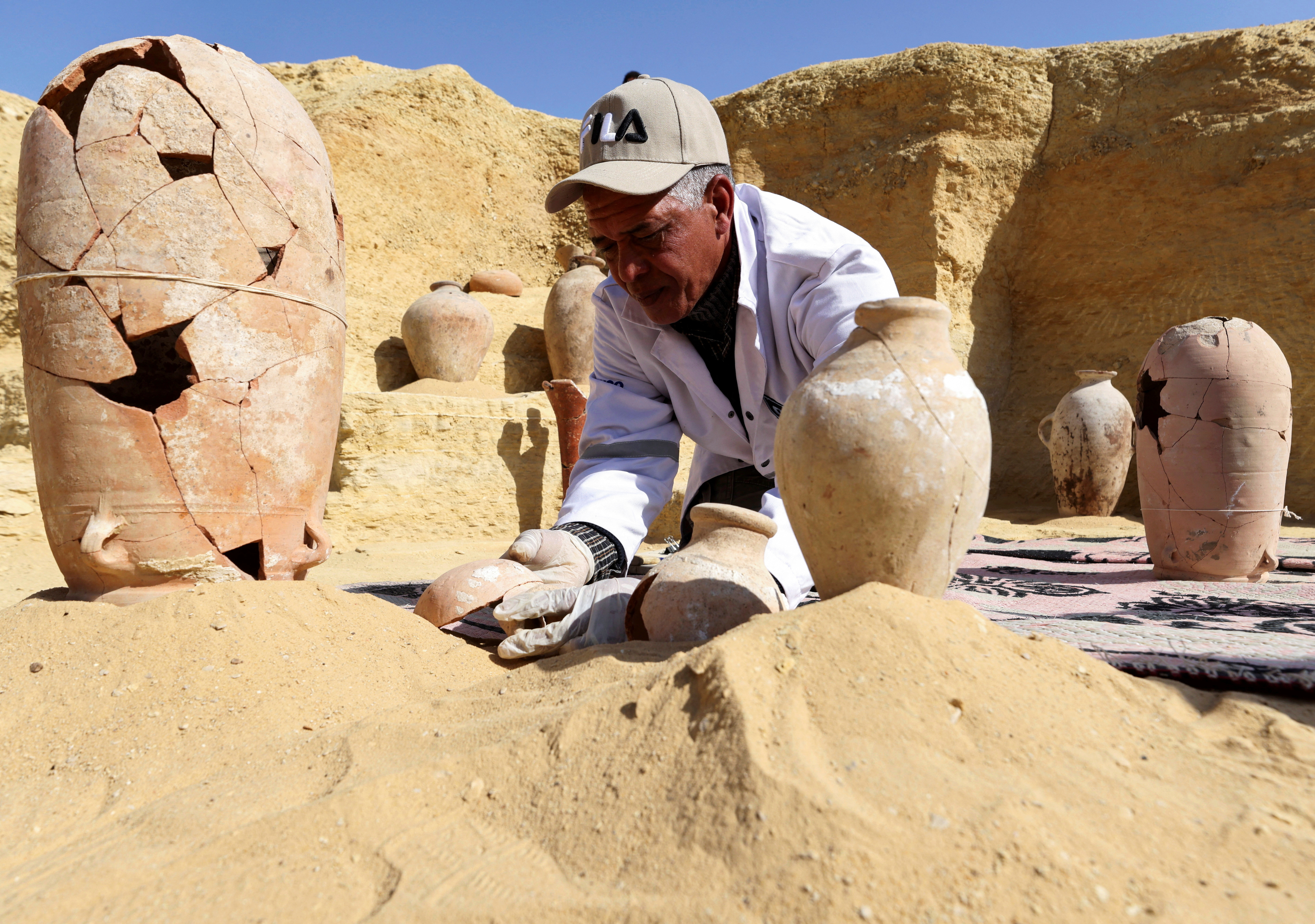 An Egyptian archaeologist restores antiquities after the announcement of the discovery of 4,300-year-old sealed tombs in Egypt's Saqqara necropolis, in Giza