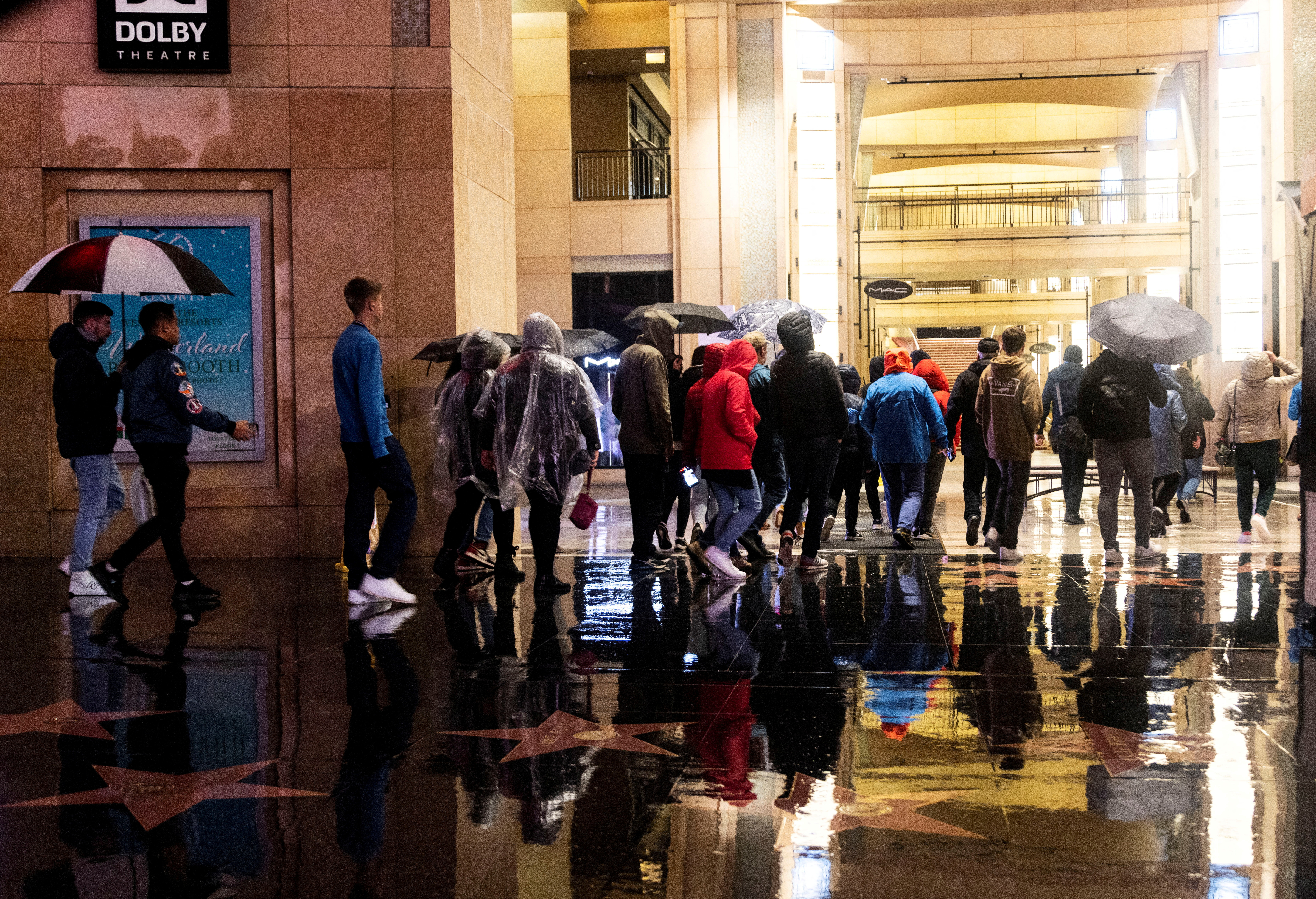 A group of tourists walk on Hollywood Boulevard during an ongoing rain storm in Los Angeles
