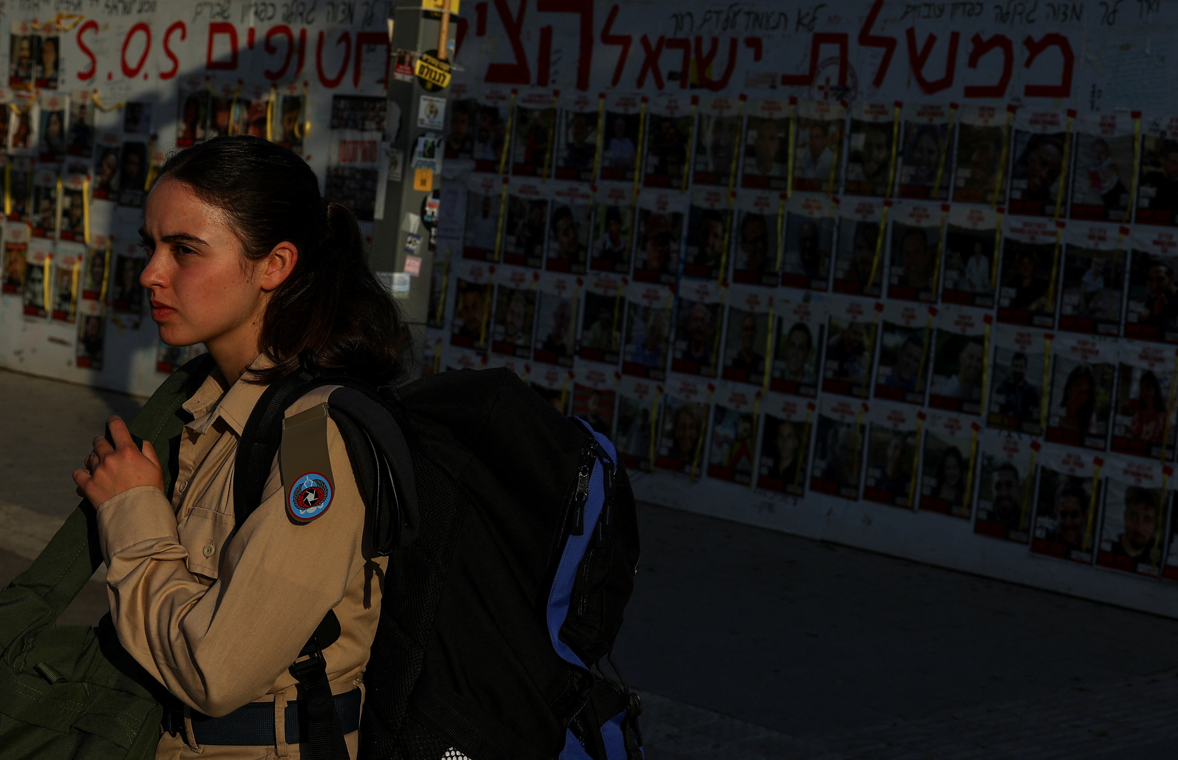 A girl stands near posters with pictures of hostages kidnapped in the October 7 attack by Hamas, in Tel Aviv