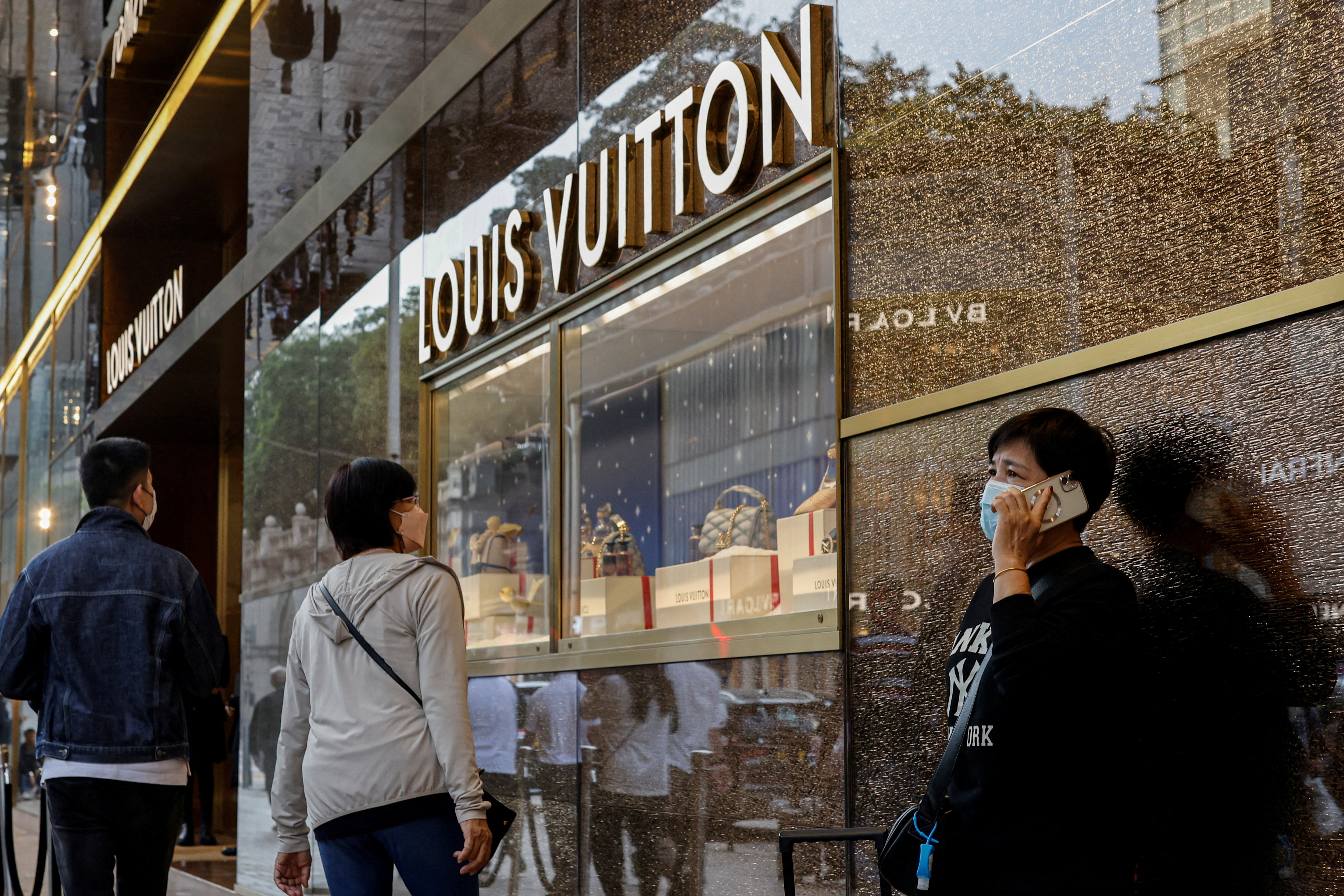 People walk past a Louis Vuitton store in Tsim Sha Tsui, a bustling shopping hotspot, in Hong Kong