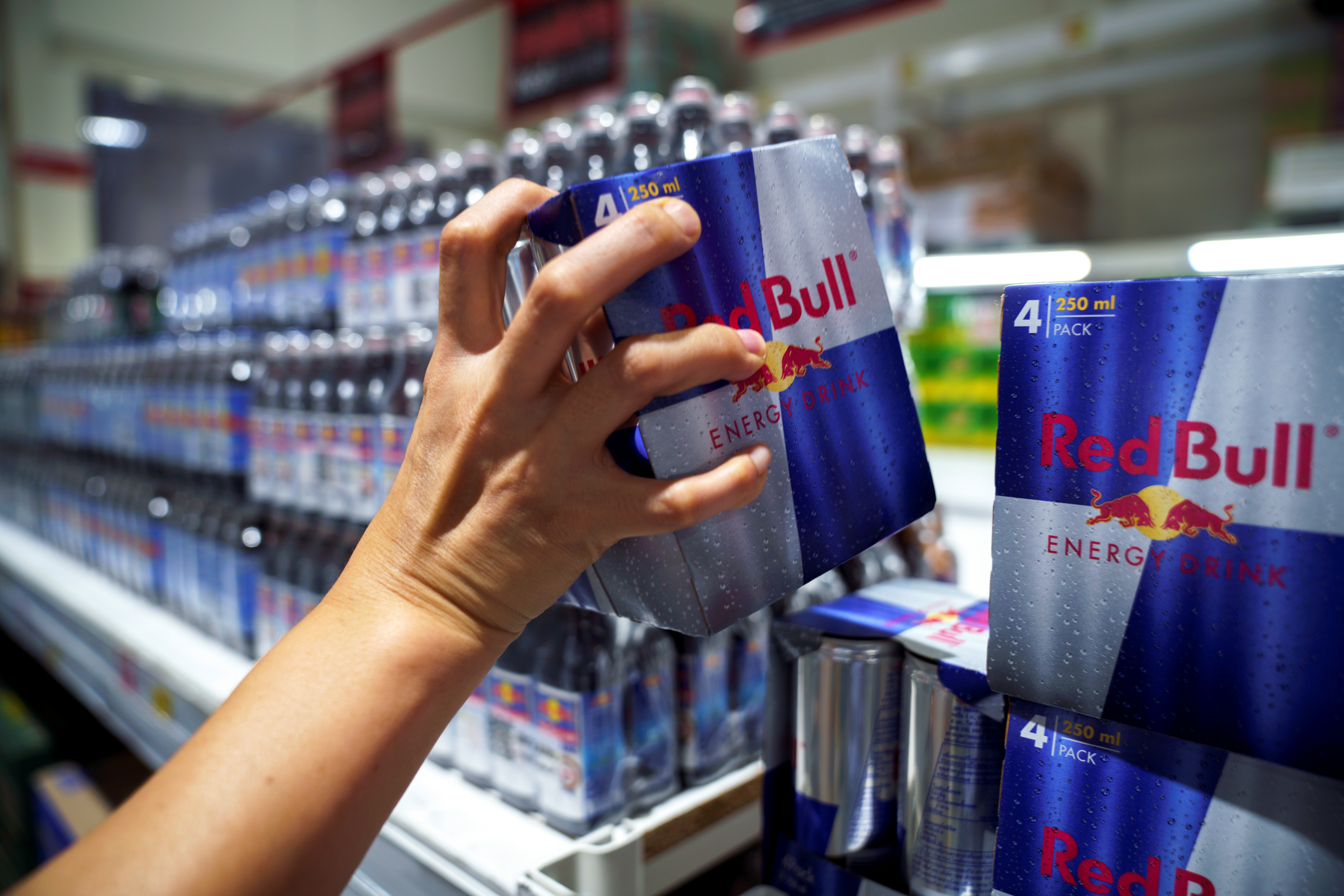 Woman buys Red Bull energy drink cans in a supermarket in Bangkok