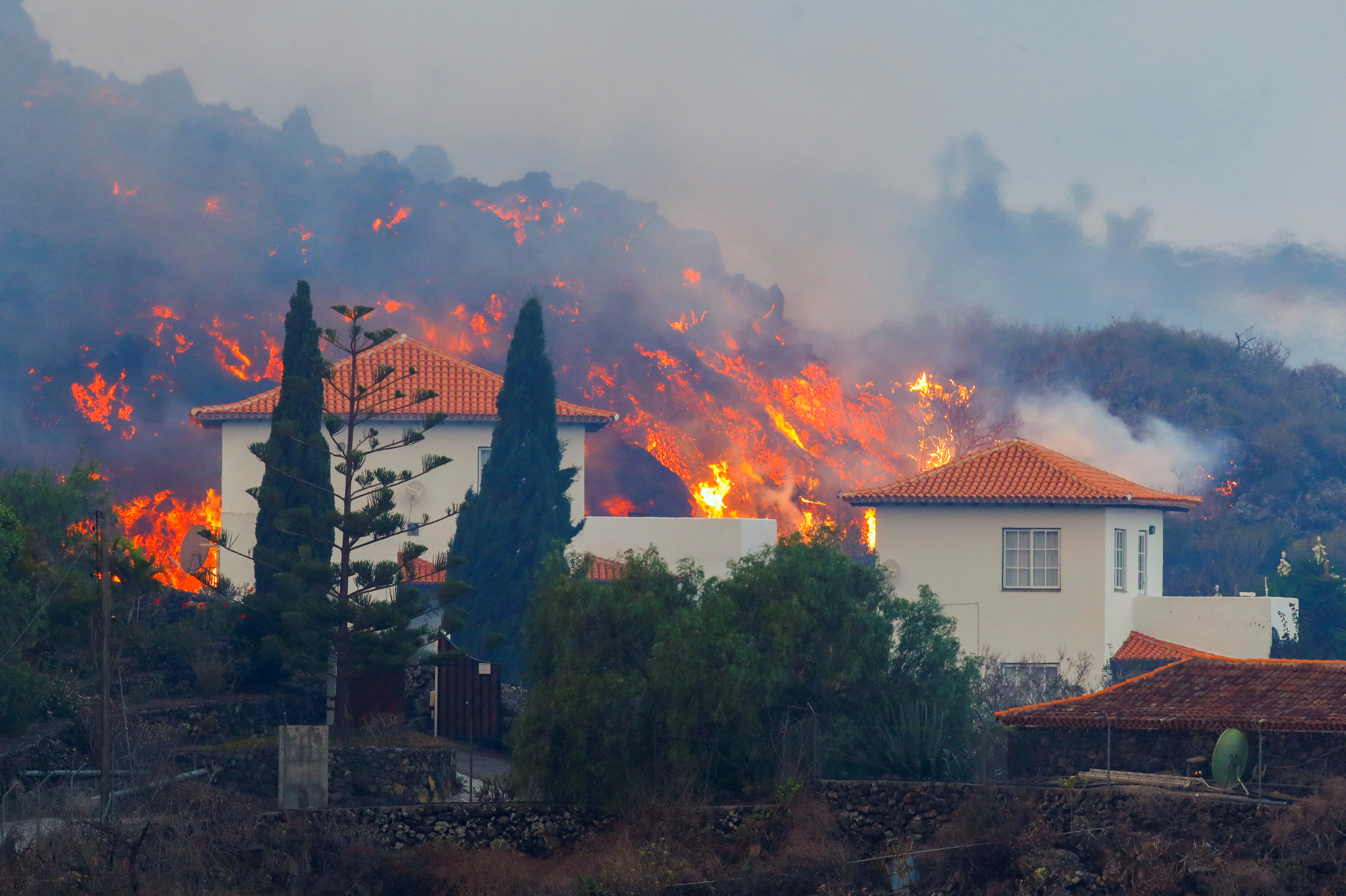 Lava flows behind a house following the eruption of a volcano in Spain