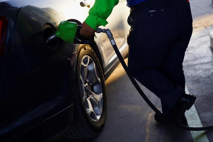 A worker fills a car belonging to a Texas resident, with gasoline at a gas station following increased fuel prices in U.S., in Ciudad Juarez