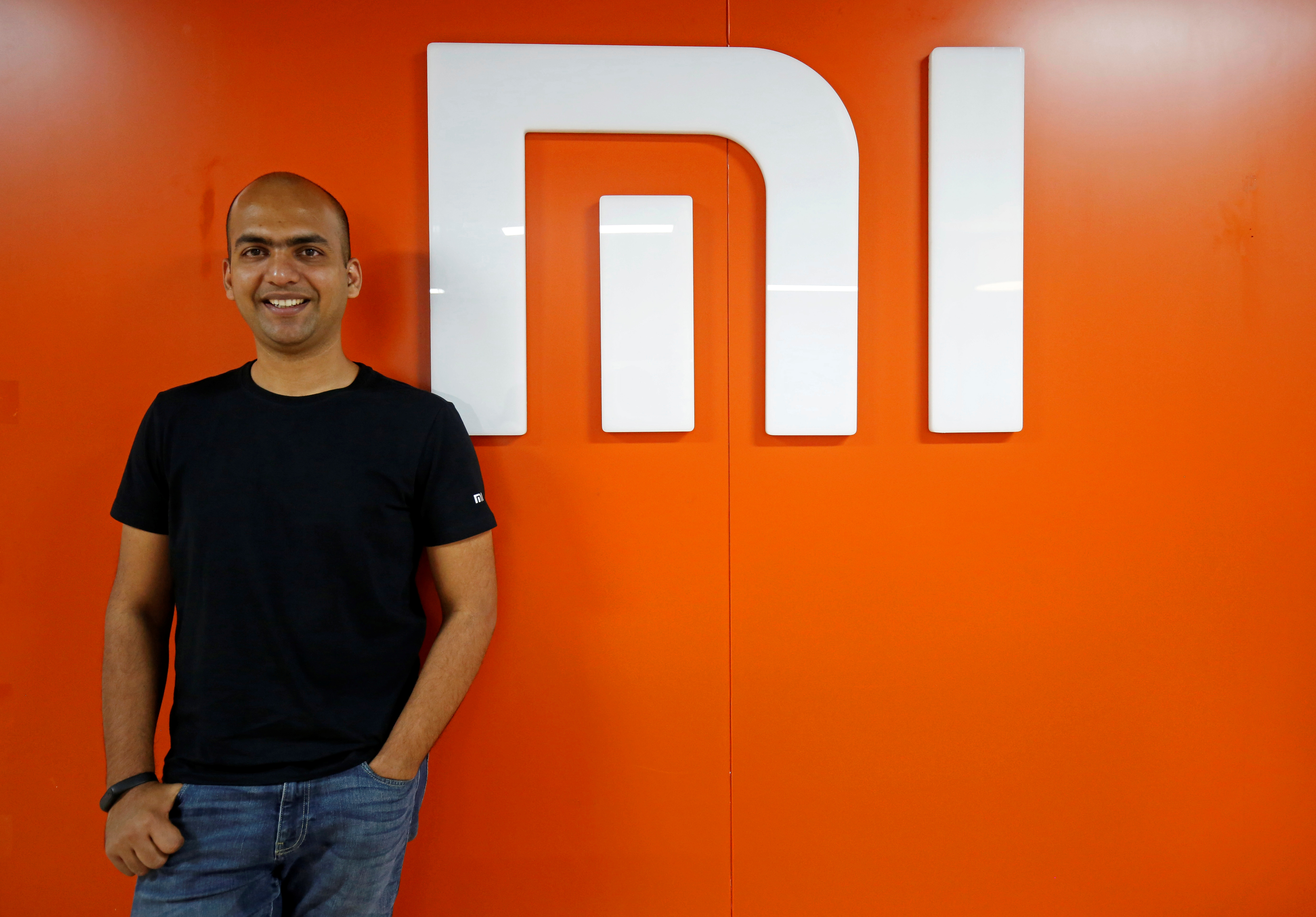 Manu Kumar Jain, Managing Director of Xiaomi India, poses next to the logo of Xiaomi after an interview with Reuters inside his office in Bengaluru