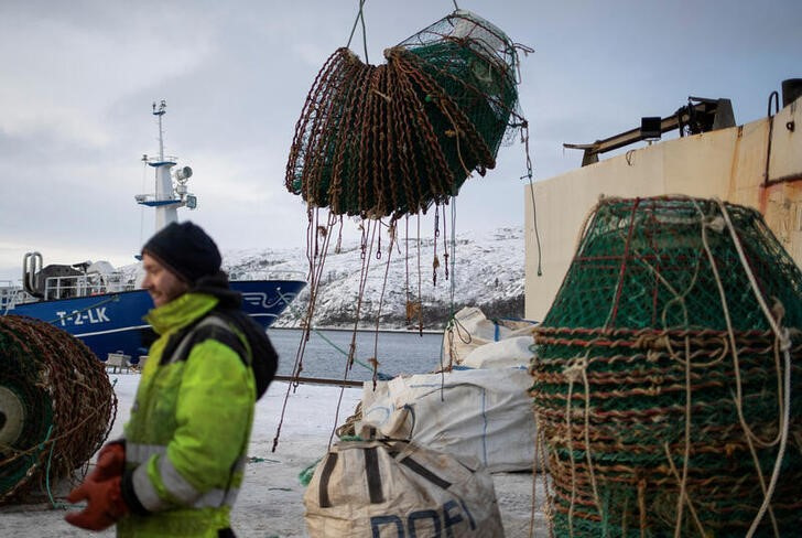 A sailor prepares to offload fishing equipment from a snow crab fishing vessel in Norway,