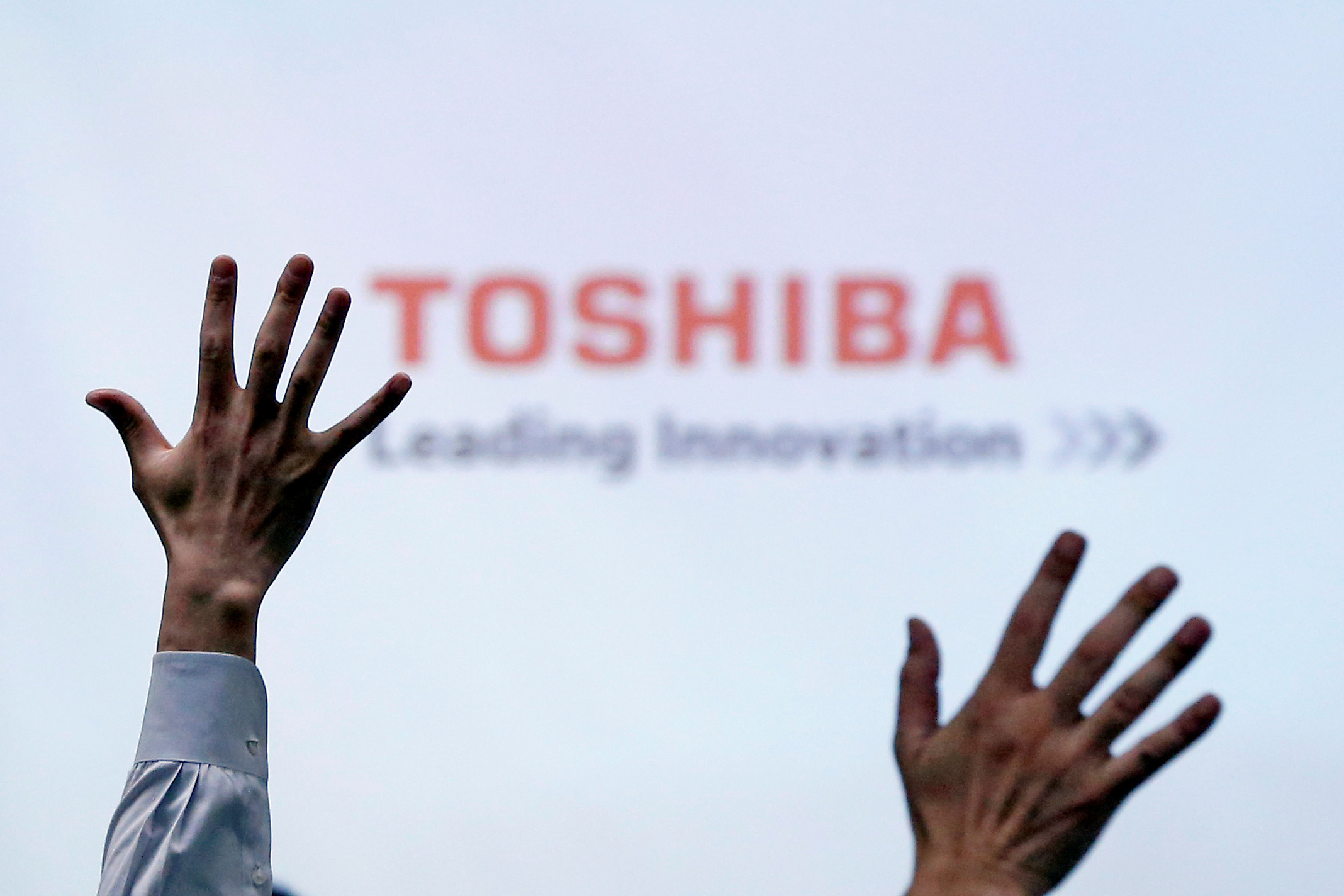 Reporters raise their hands for a question during a news conference by Toshiba Corp CEO Satoshi Tsunakawa at the company headquarters in Tokyo