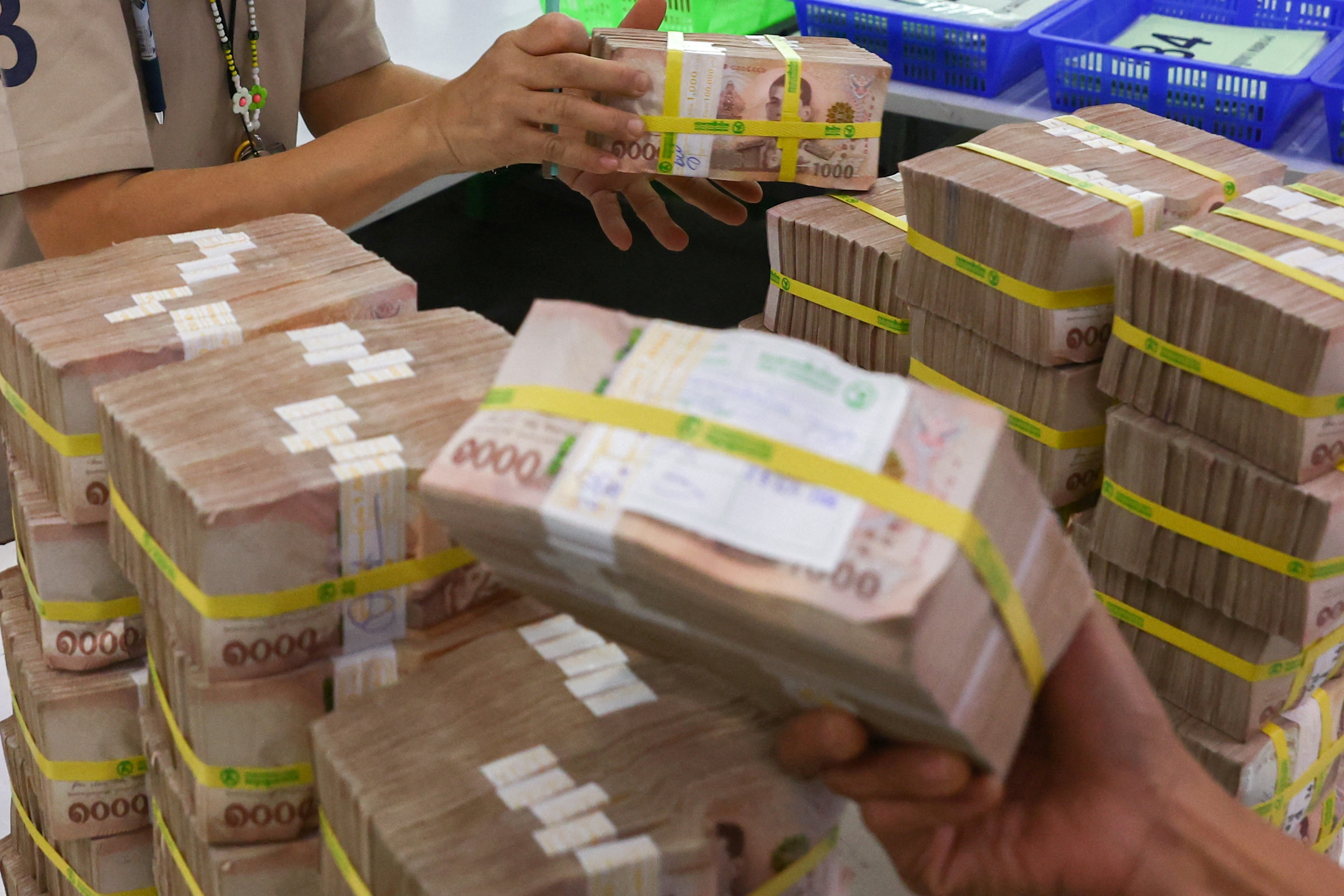 Bank employees gather Thai baht notes at a Kasikornbank in Bangkok