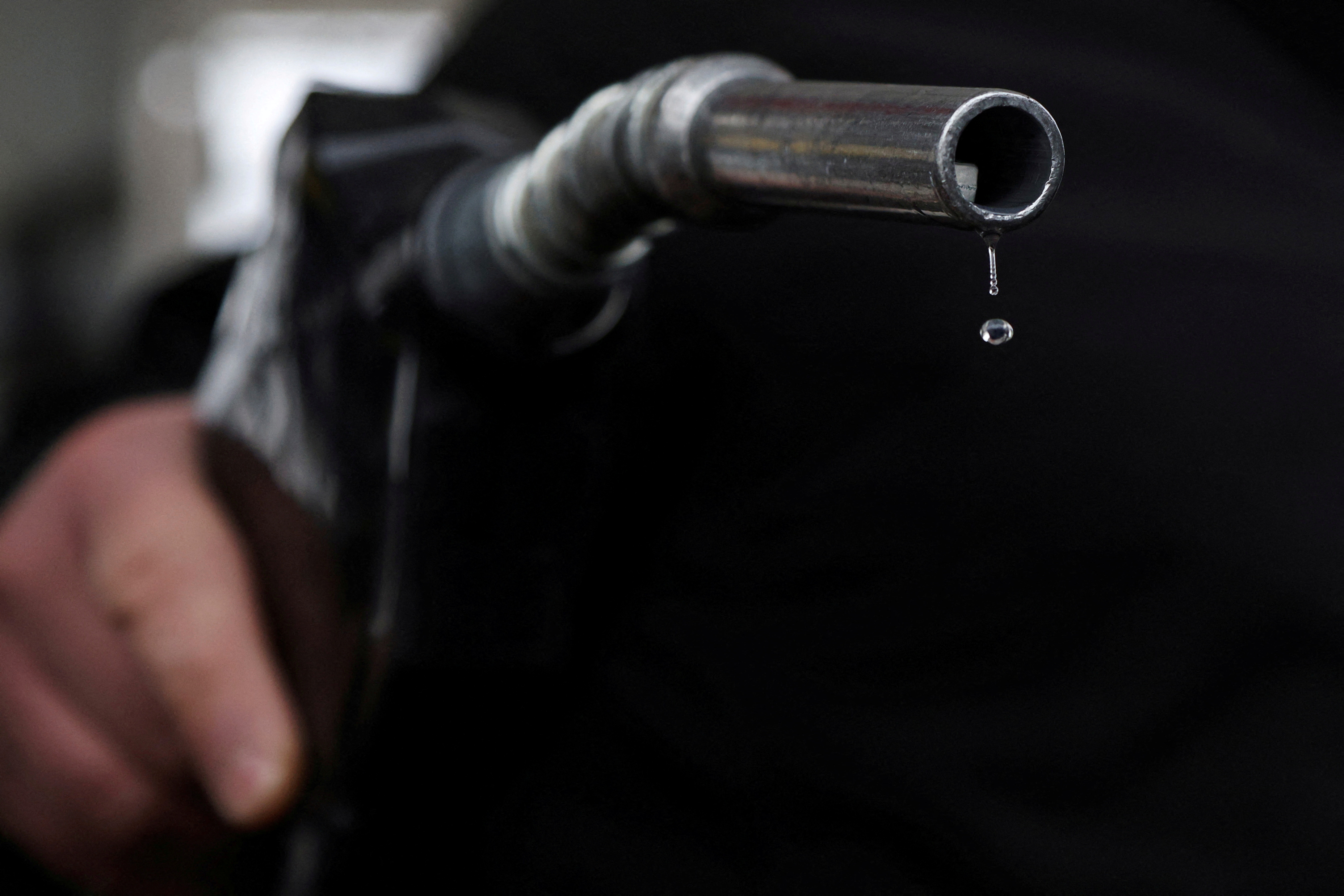 Gasoline drips out of a nozzle held by a gas station mechanic in Somerville