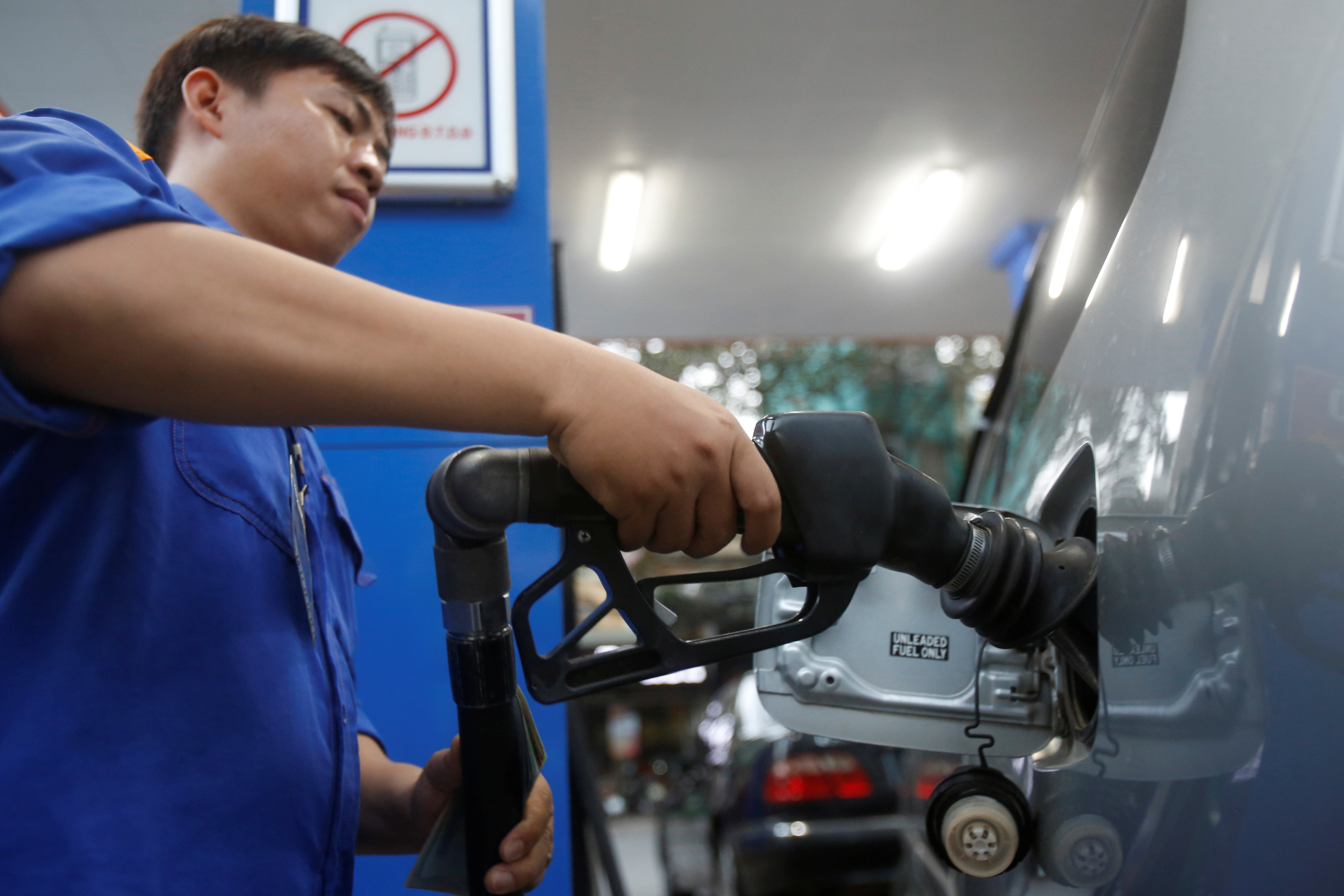 An employee pumps petrol into a car at a petrol station in Hanoi