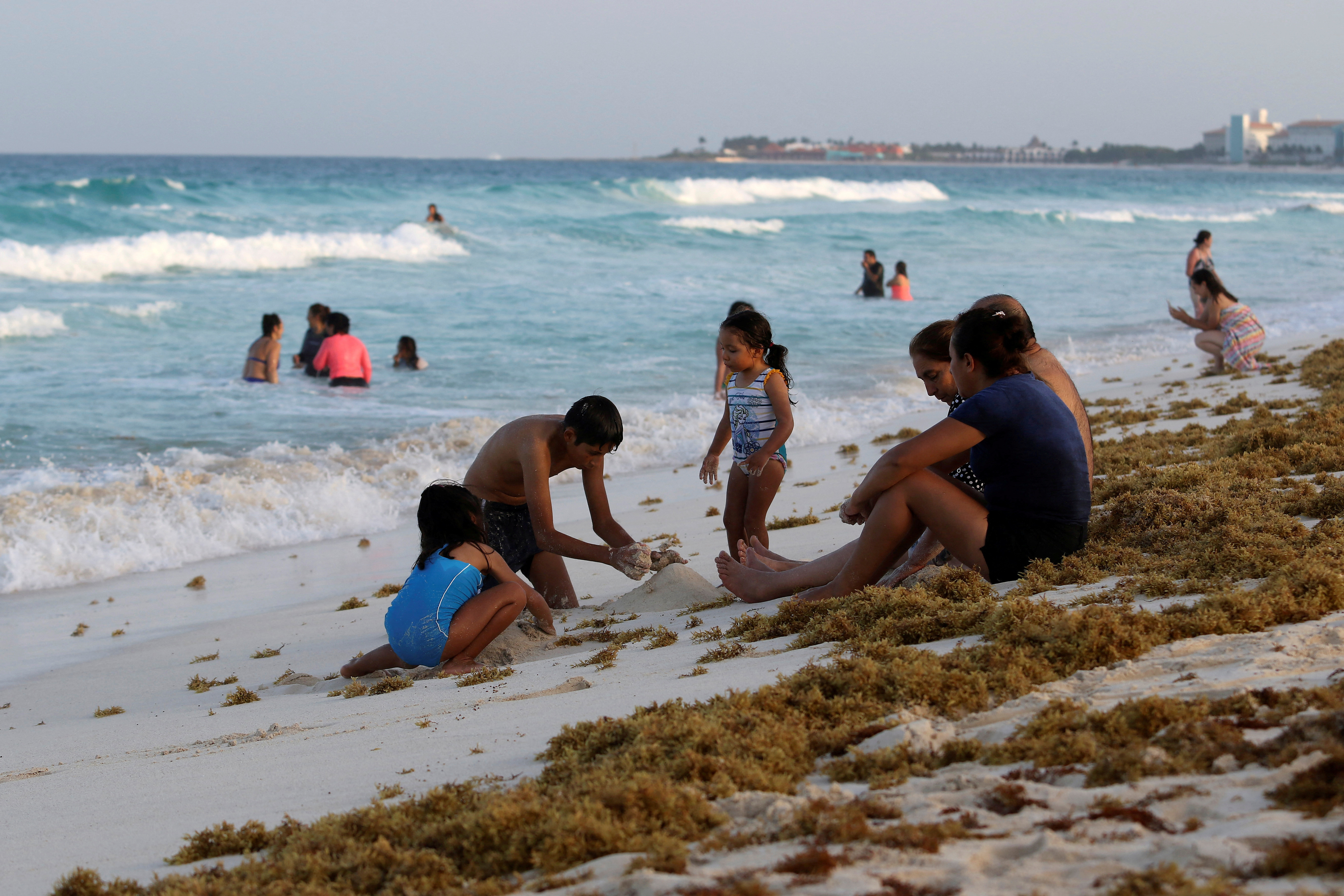 Tourists are seen on a beach covered with seaweed in Cancun