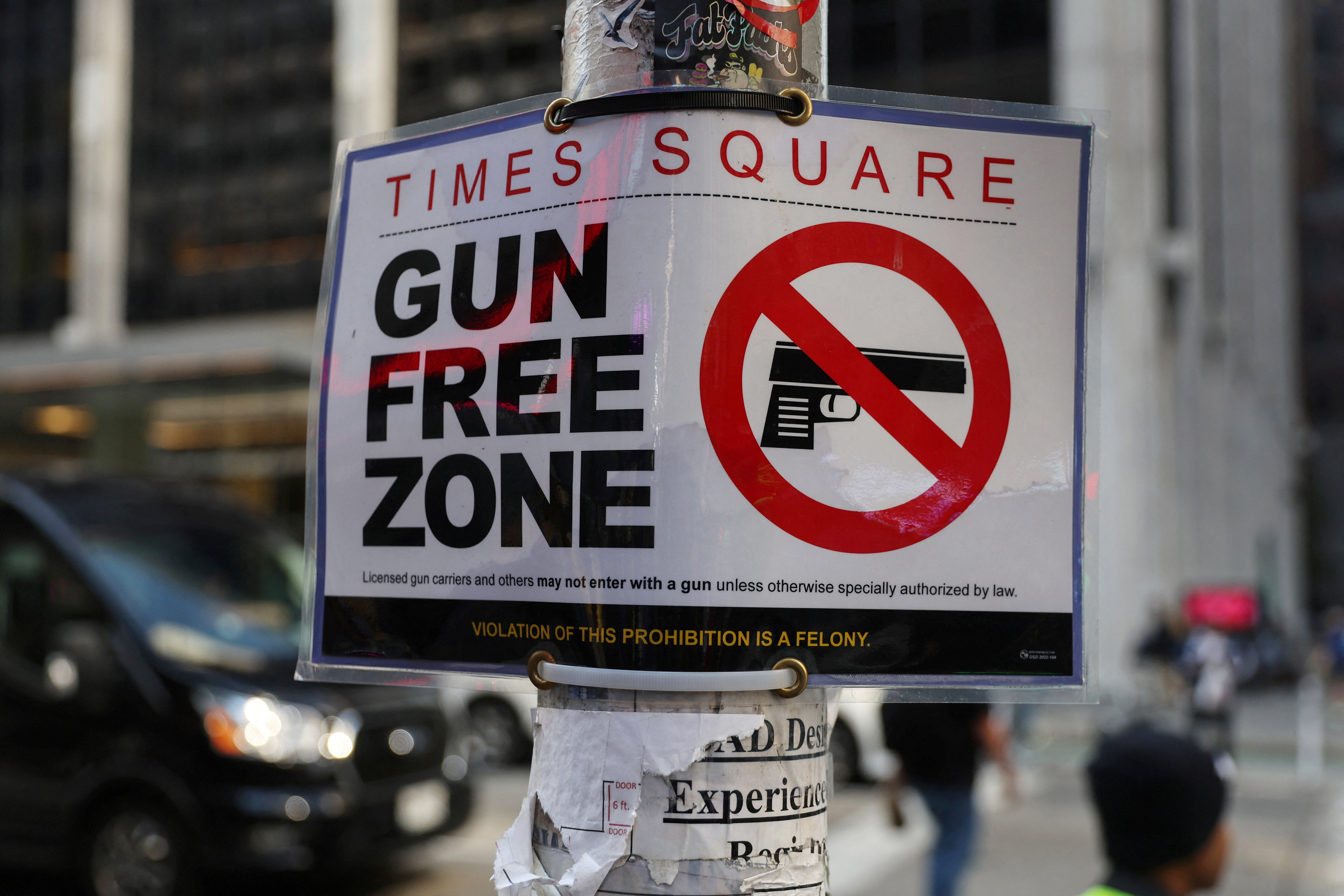 Times Square Gun Free Zone sign hangs from a light pole on 6th avenue in New York City