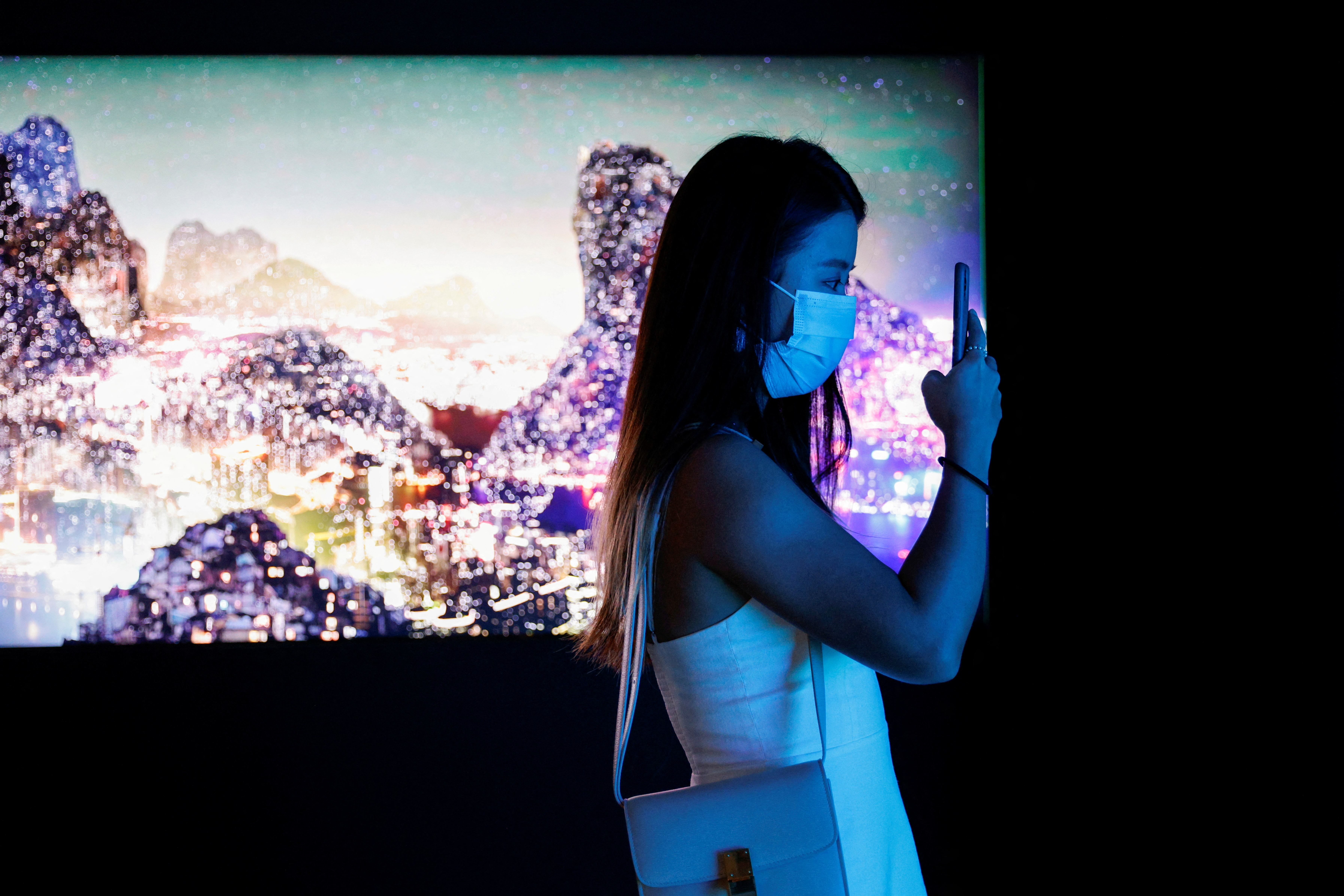 Visitor takes a photo in front of a video installation which will be converted into NFTs and auctioned online at Sotheby's, in Hong Kong
