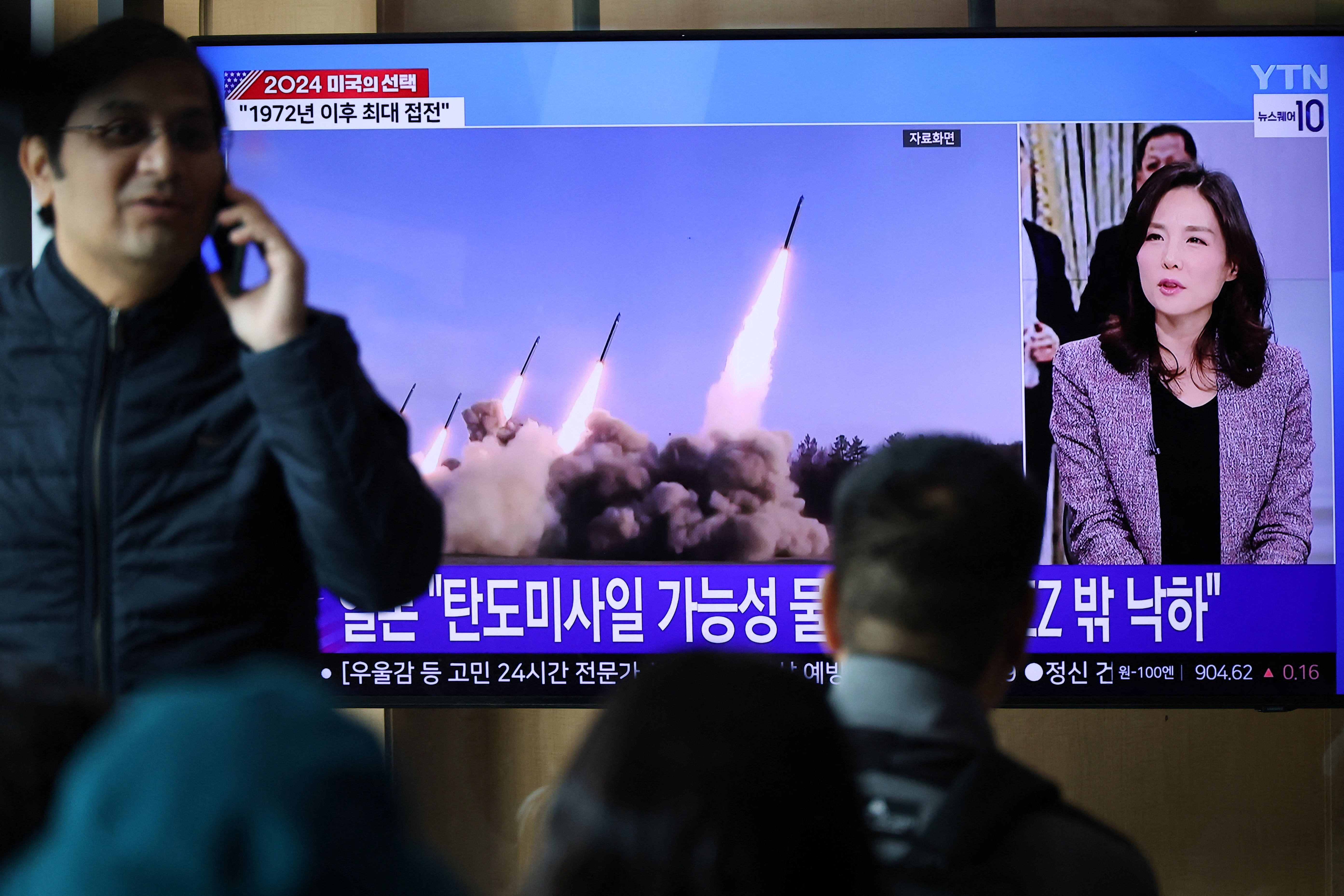 People watch a TV broadcasting a news report on North Korea firing missiles that flew 400 km after lifting off at around 7:30 a.m. from Sariwon, just south of the capital Pyongyang, at a railway station in Seoul