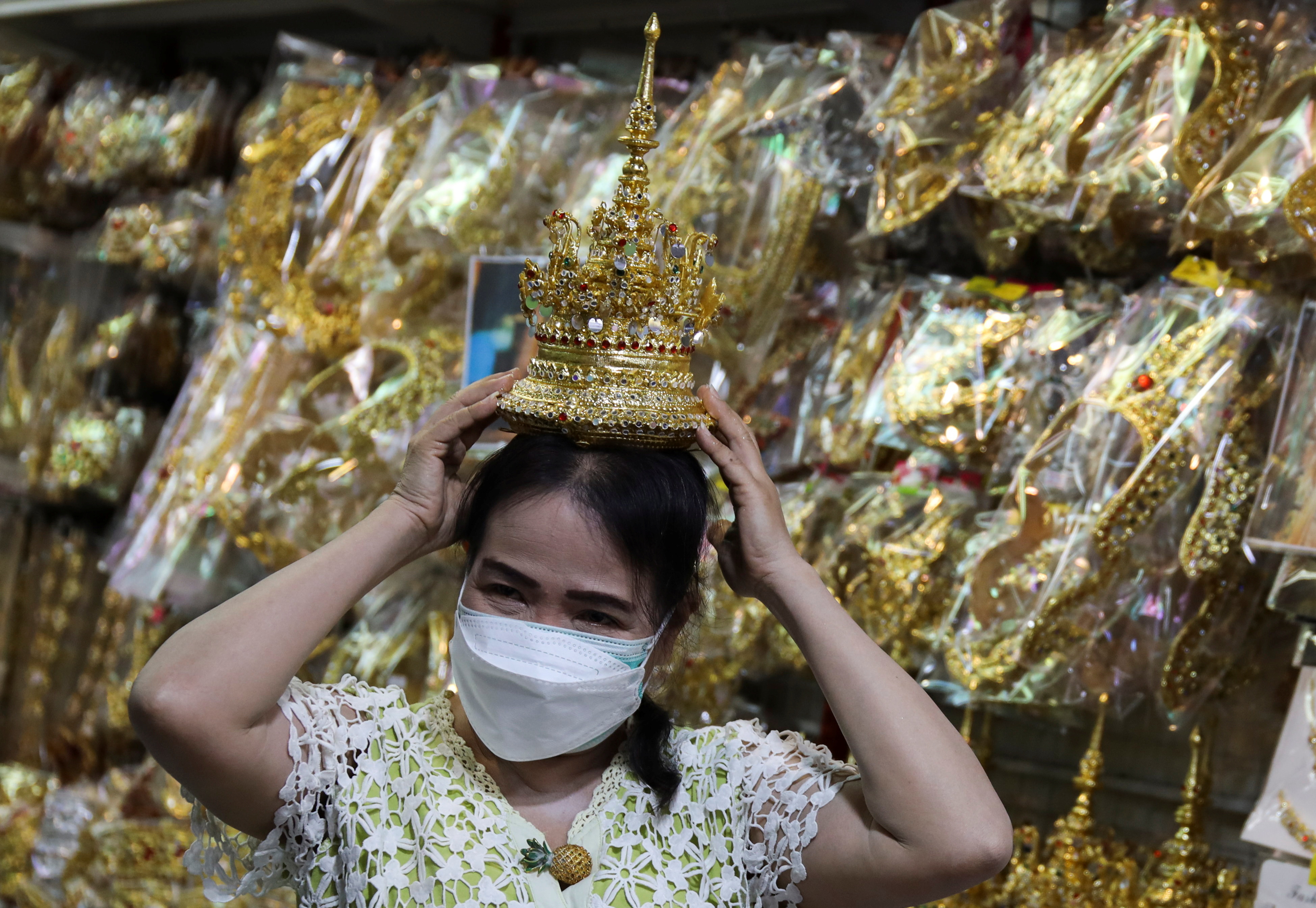 Shop keeper displays a Thai traditional costume head gear similar to one wore by K-pop singer Lisa at a shop selling merchandise items in Bangkok