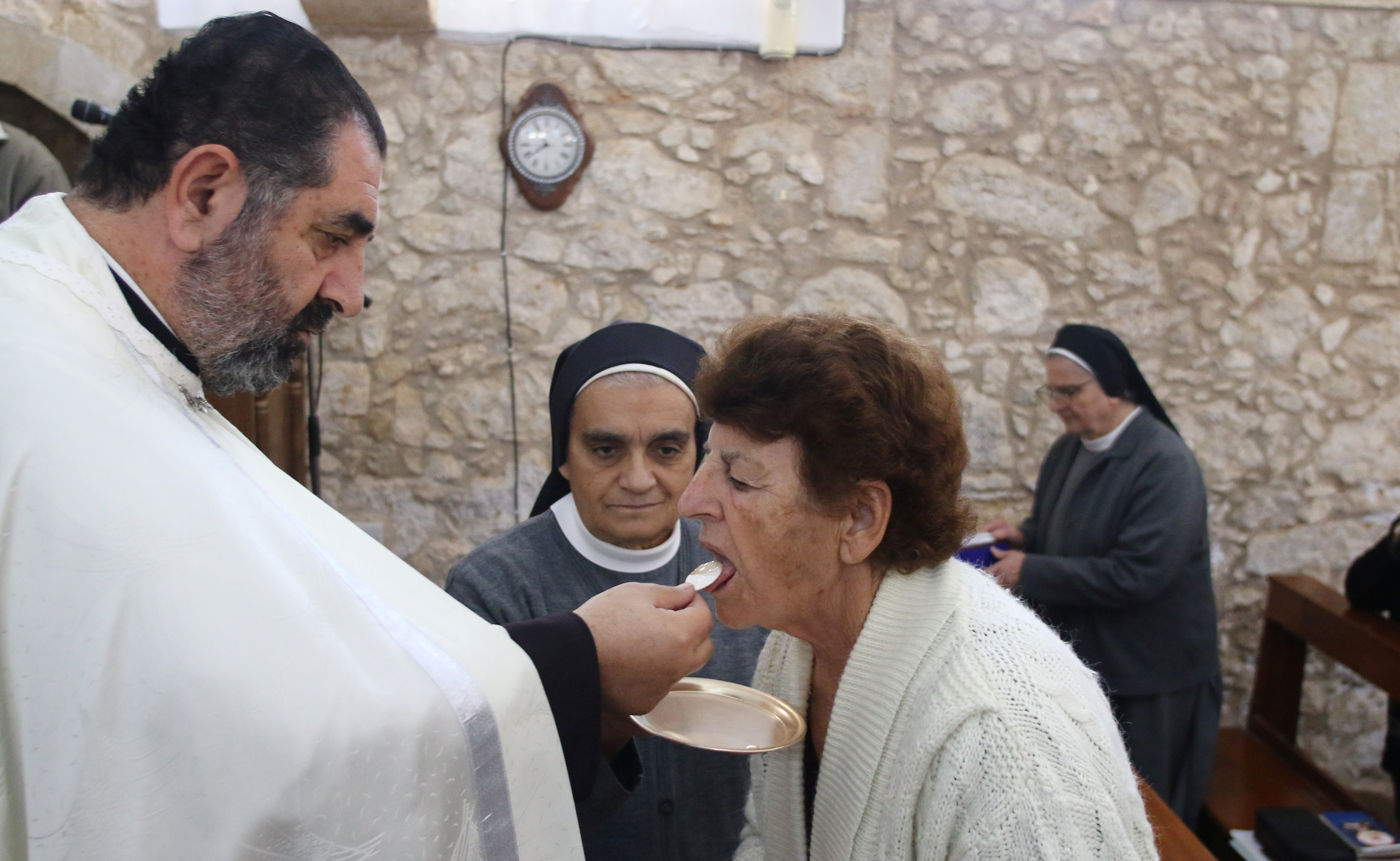 Father Iosif Skender, a Maronite priest, gives Holy Communion to a member of the congregation at the Church of St. George in Kormakitis, Cyprus November 22, 2021. REUTERS/Yiannis Kourtoglou