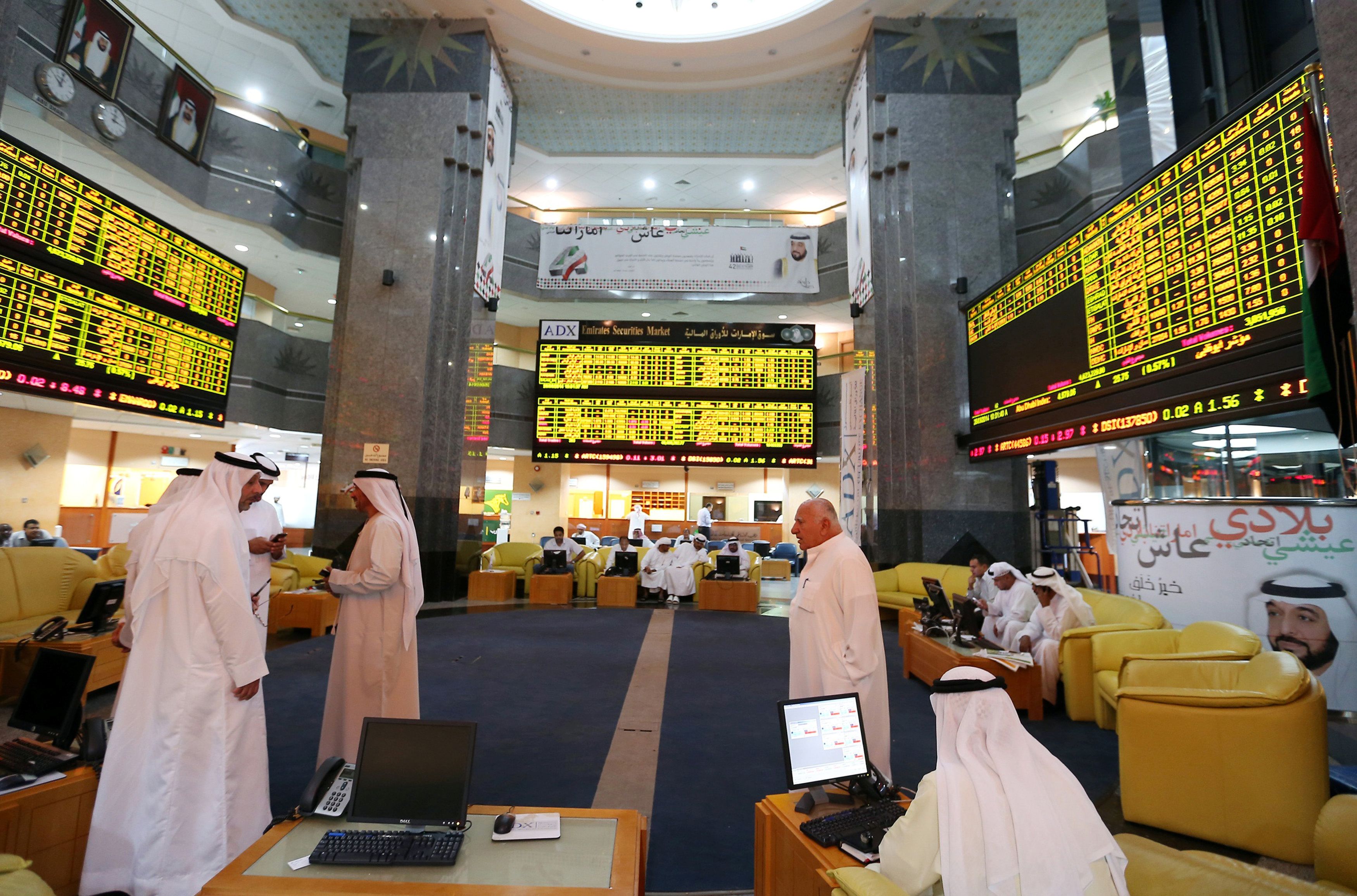 Investors monitor screens displaying stock information at the Abu Dhabi Securities Exchange
