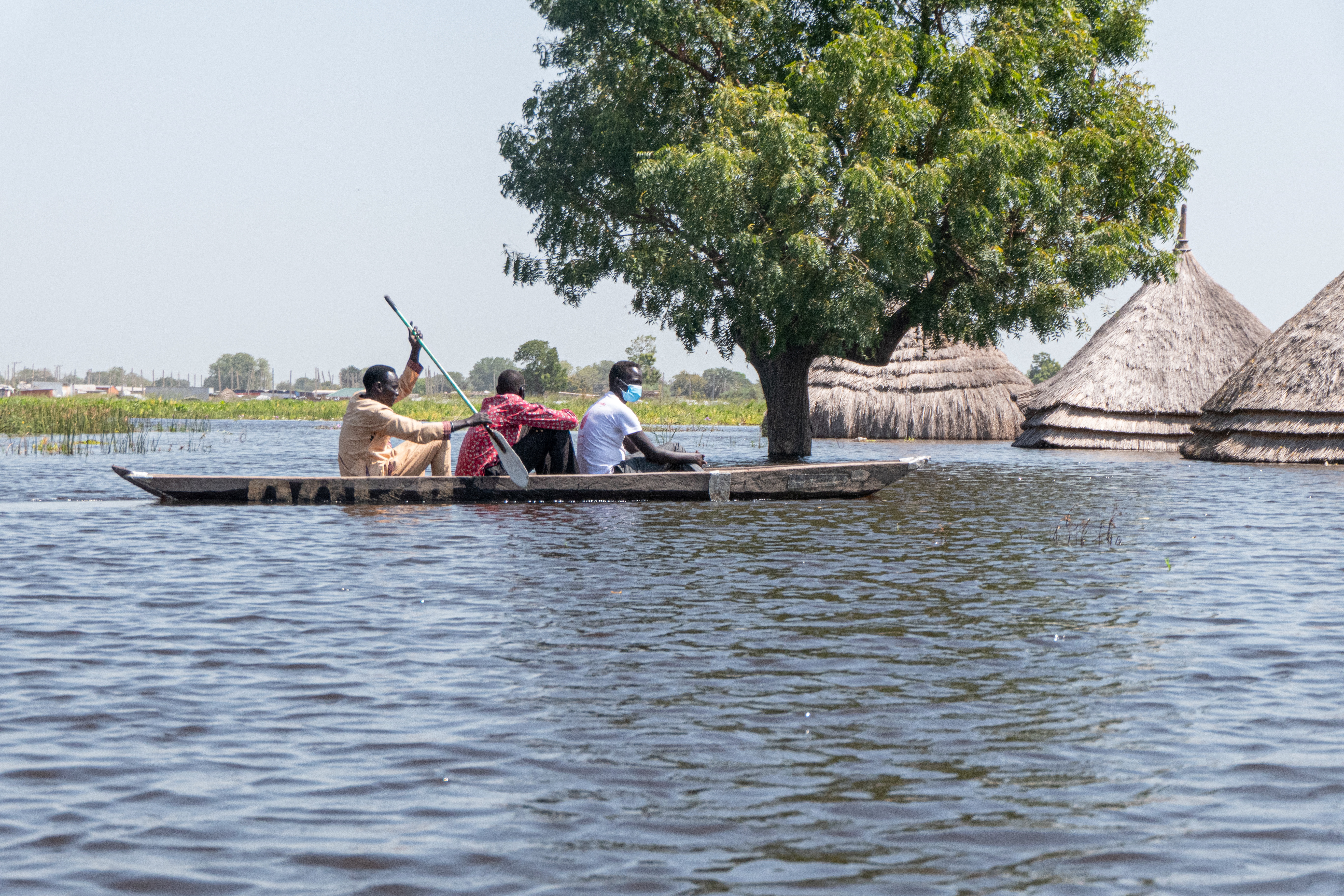 South Sudanese men navigate a canoe through flood waters in Bentiu in Unity State