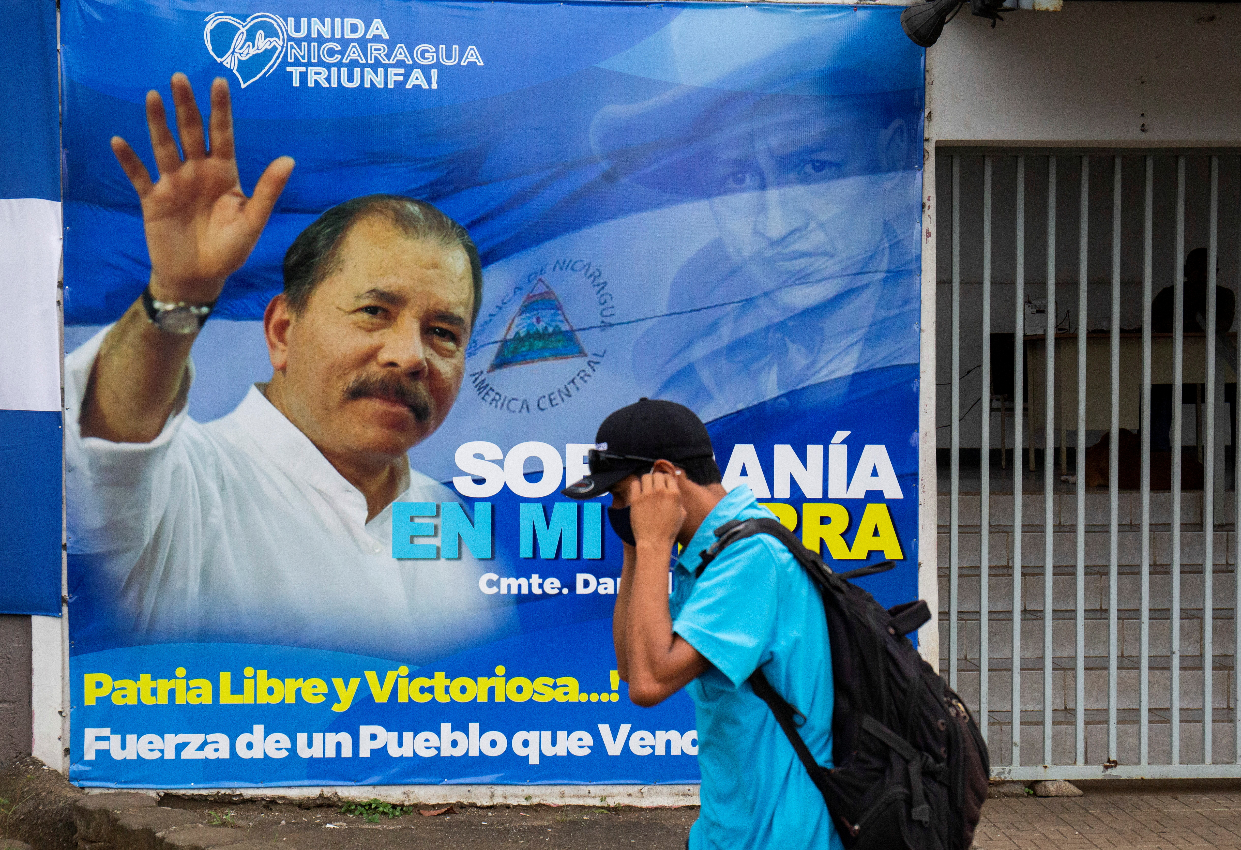 A man adjusts his face mask while walking by a banner promoting Nicaraguan President Daniel Ortega, as presidential election campaigns begin, in Managua, Nicaragua September 25, 2021. REUTERS/Maynor Valenzuela 