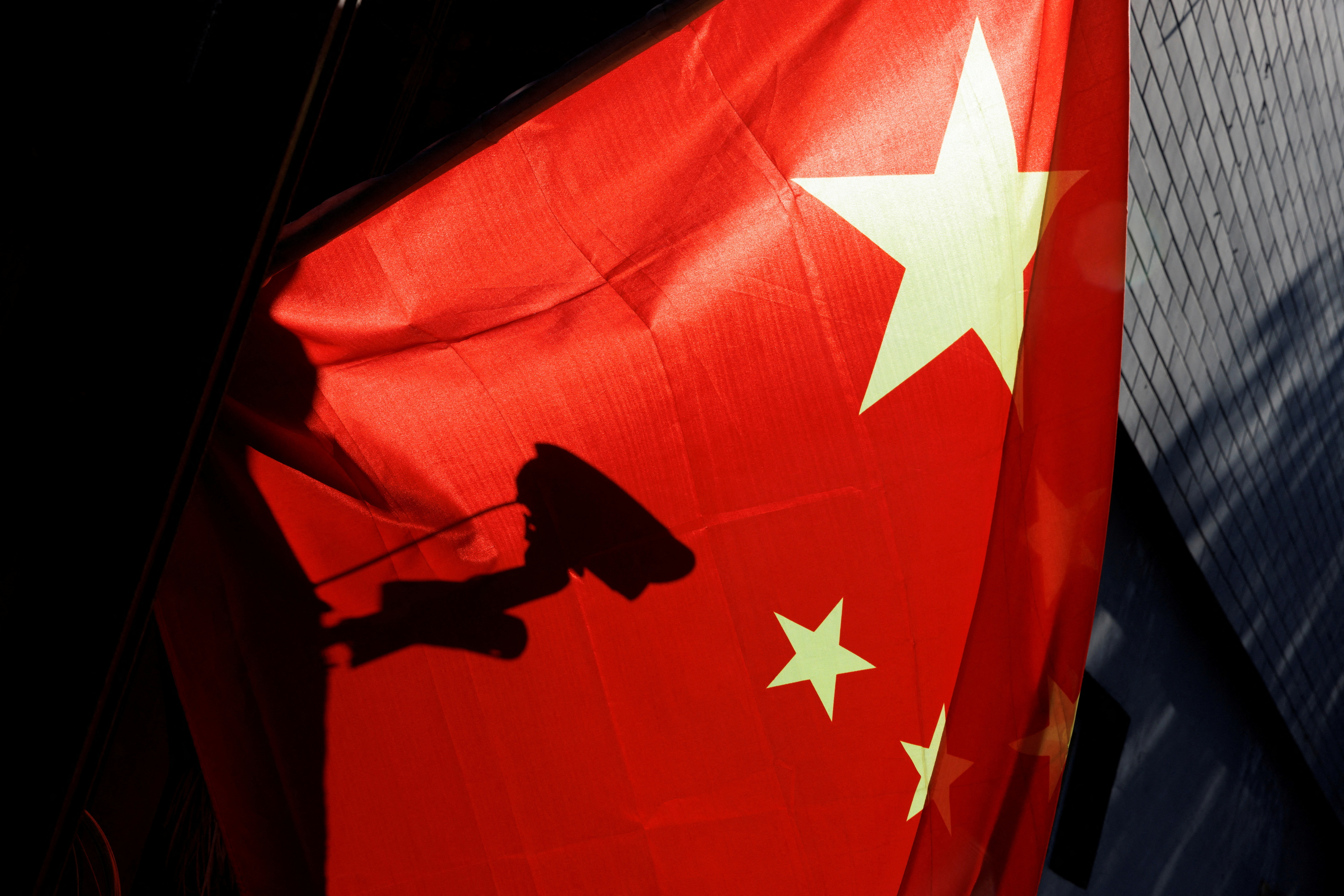 FILE PHOTO:A surveillance camera is silhouetted behind a Chinese national flag in Beijing