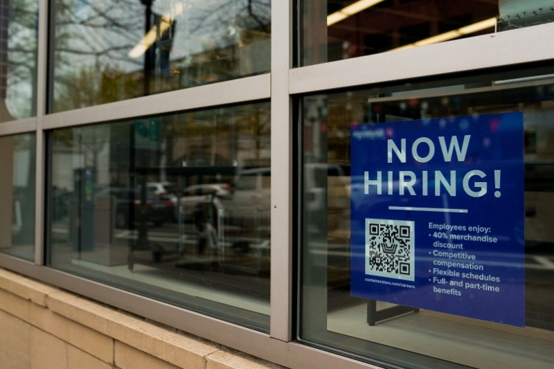 An employee hiring sign with a QR code is seen in a window of a business in Arlington