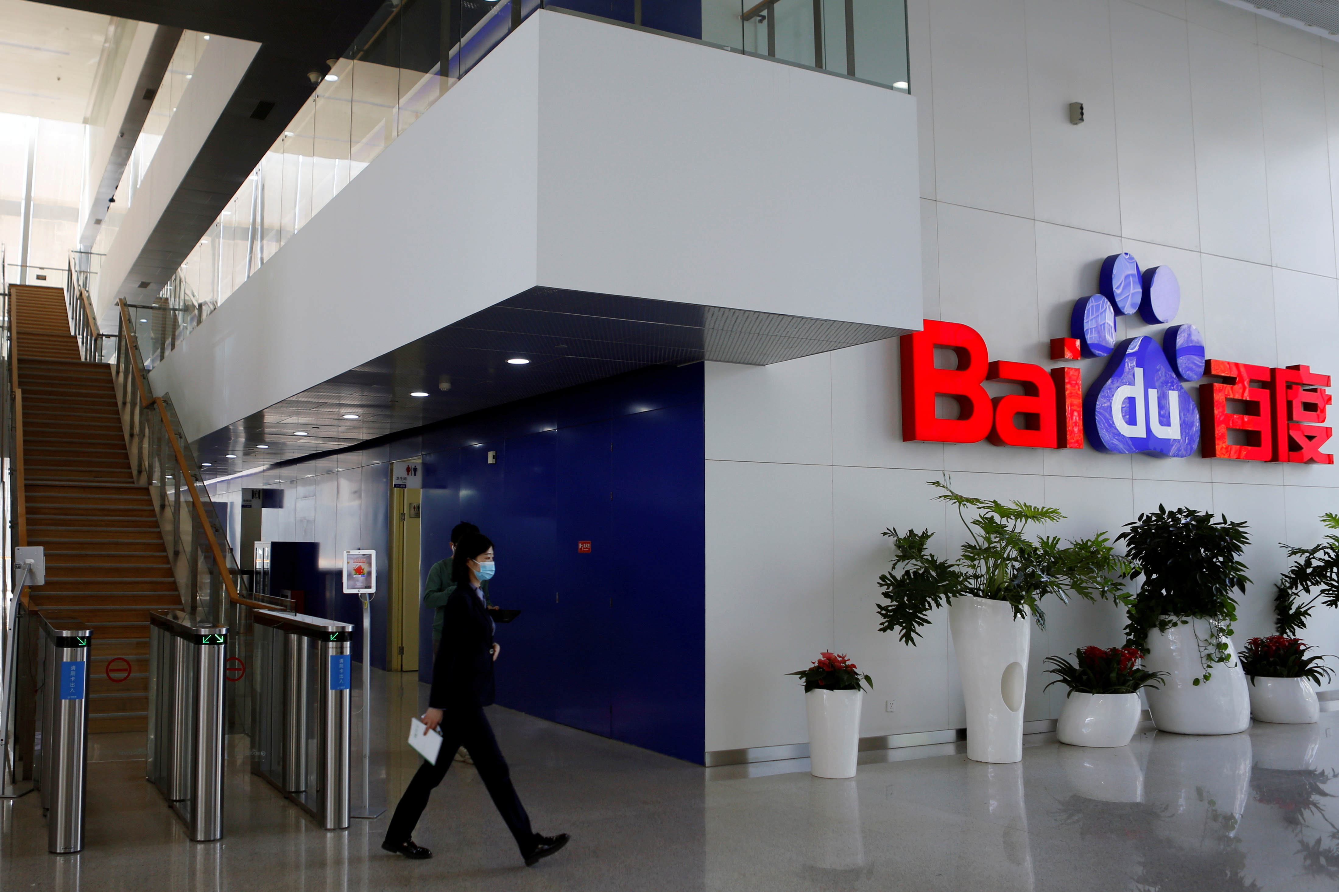 People walk near a Baidu logo at the company headquarters in Beijing
