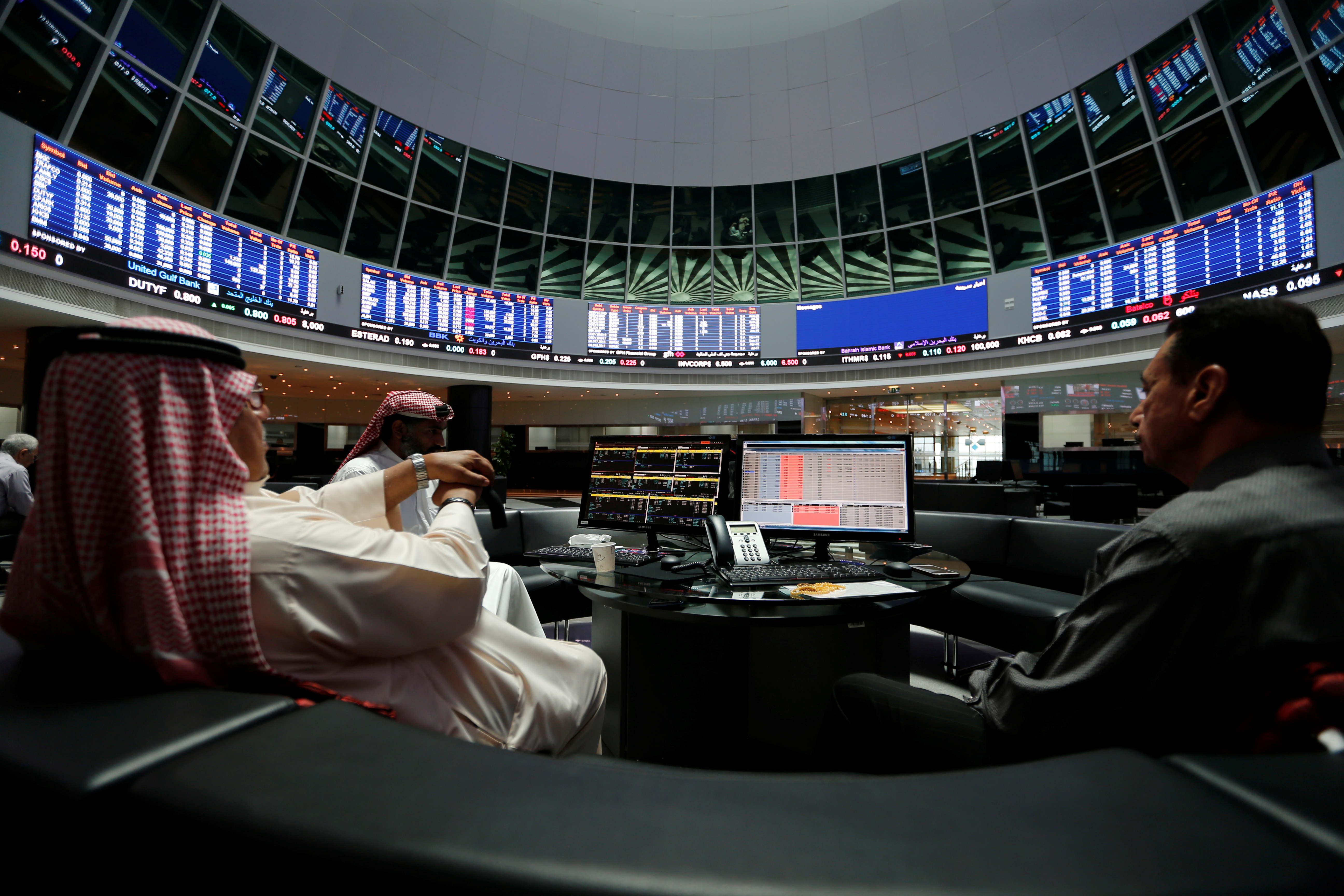 Traders chat during early hours after opening of the Bahrain stock market, in Manama