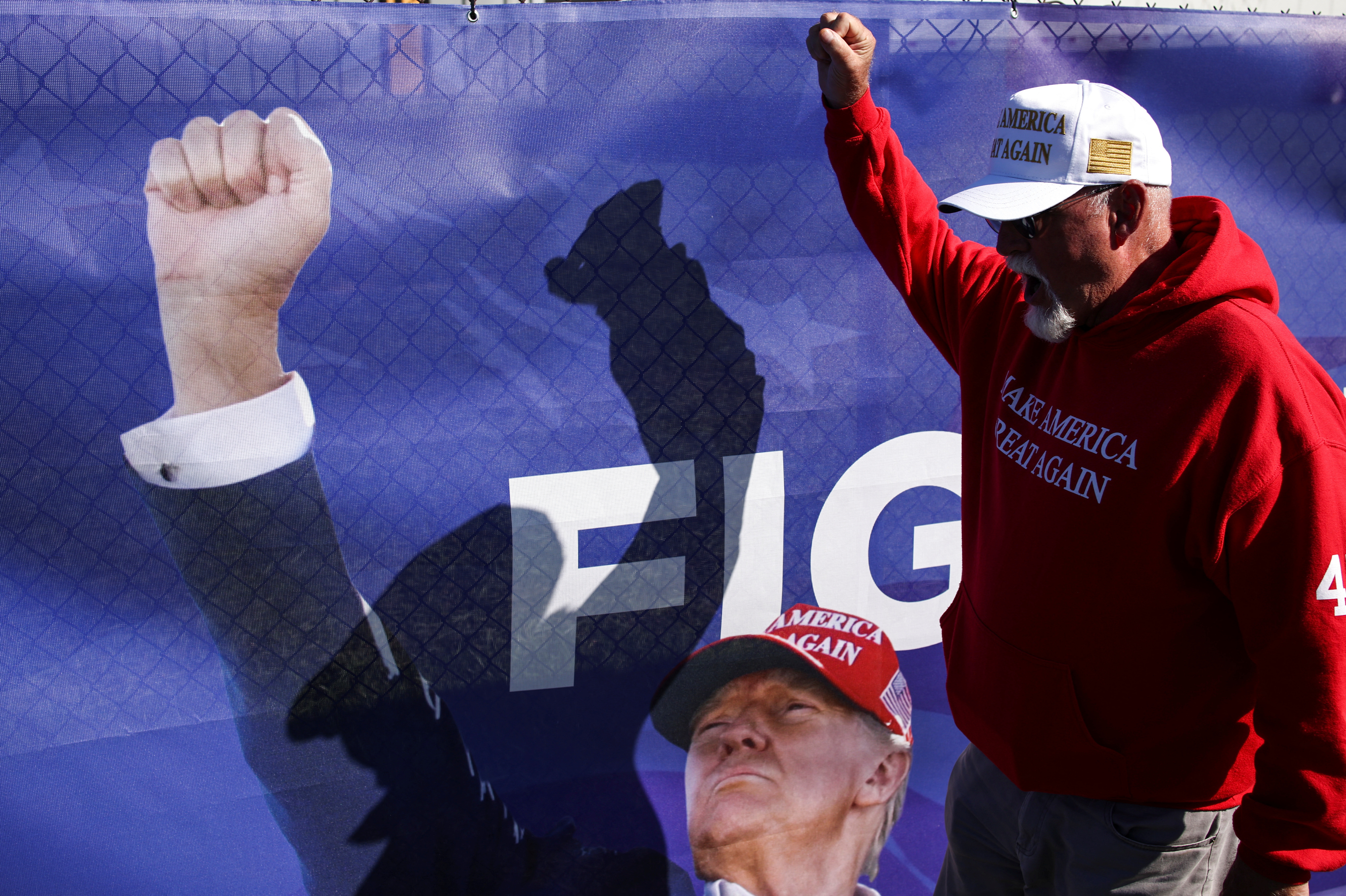 A man gestures next to a banner in support of Republican presidential nominee and former U.S. president Donald Trump, on the day Trump returns to the site of the July assassination attempt against him in Butler, Pennsylvania, U.S., October 5, 2024. REUTERS/Carlos Barria