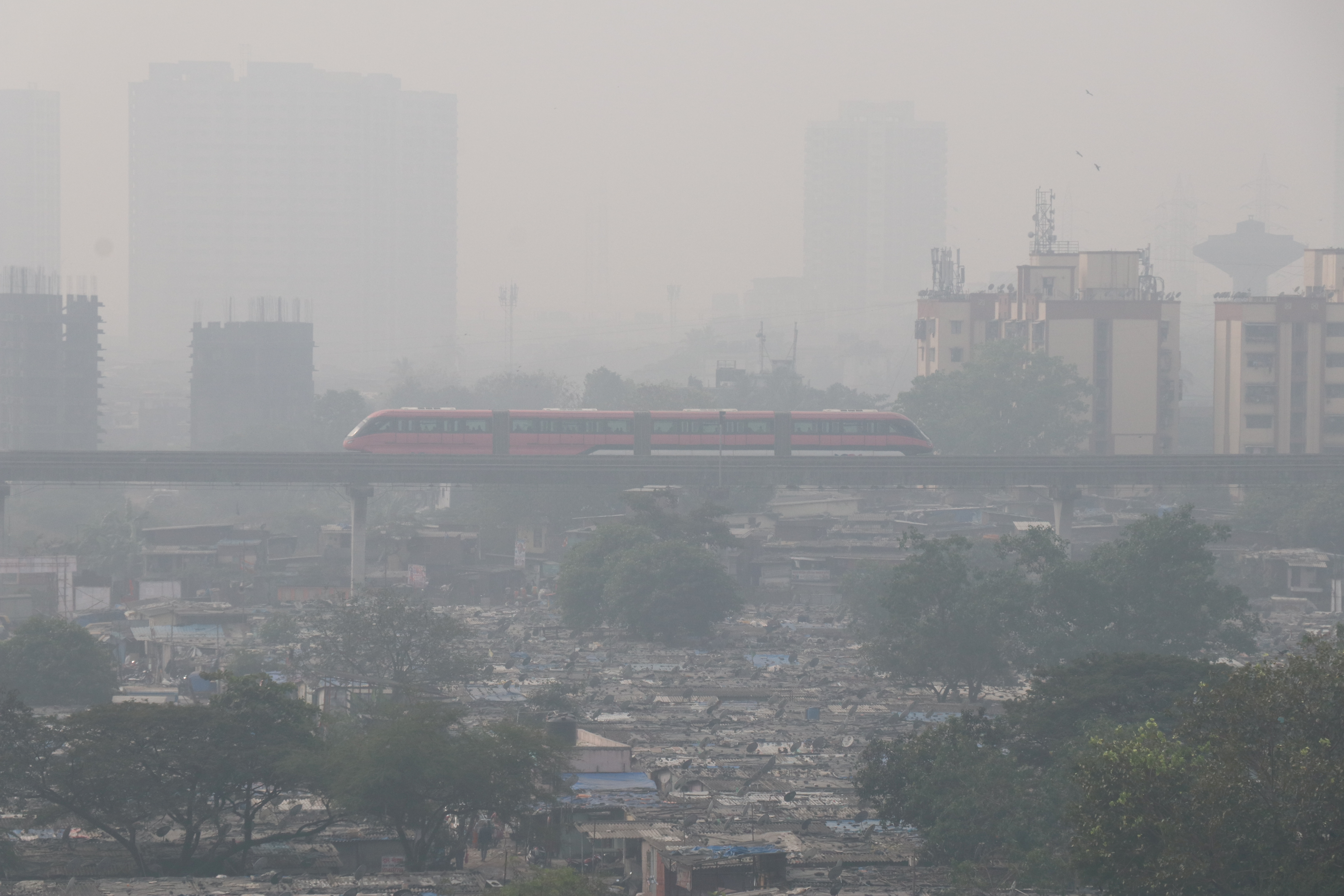 Mumbai Monorail passes through a slum area on a smoggy morning in Mumbai