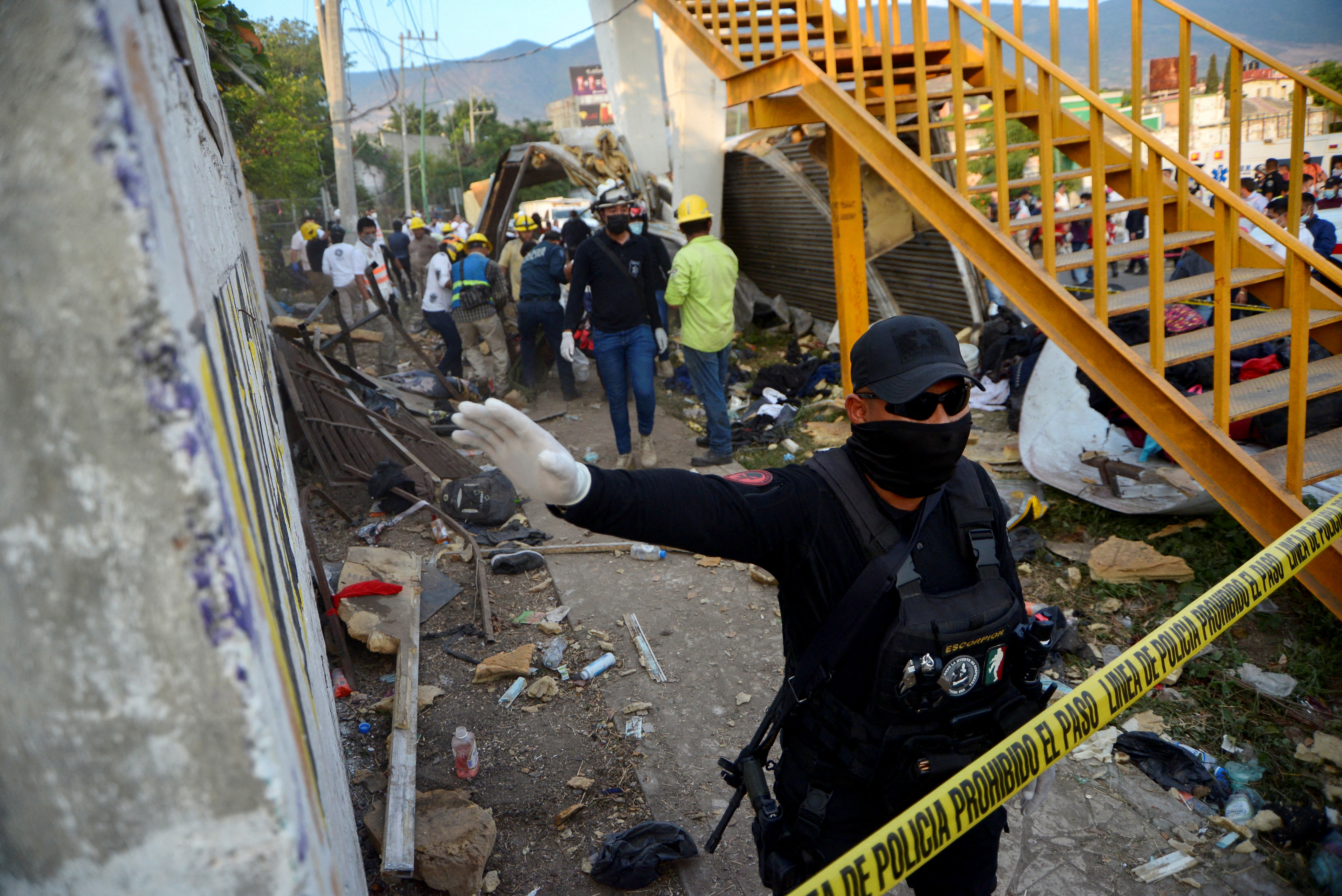 A police officer raises his arm to block photographers to to avoid taking pictures at the site of a trailer accident that left at least 49 people dead, most of them migrants from Central America, in Tuxtla Gutierrez, in Chiapas state, Mexico December 9, 2021. REUTERS/Jacob Garcia