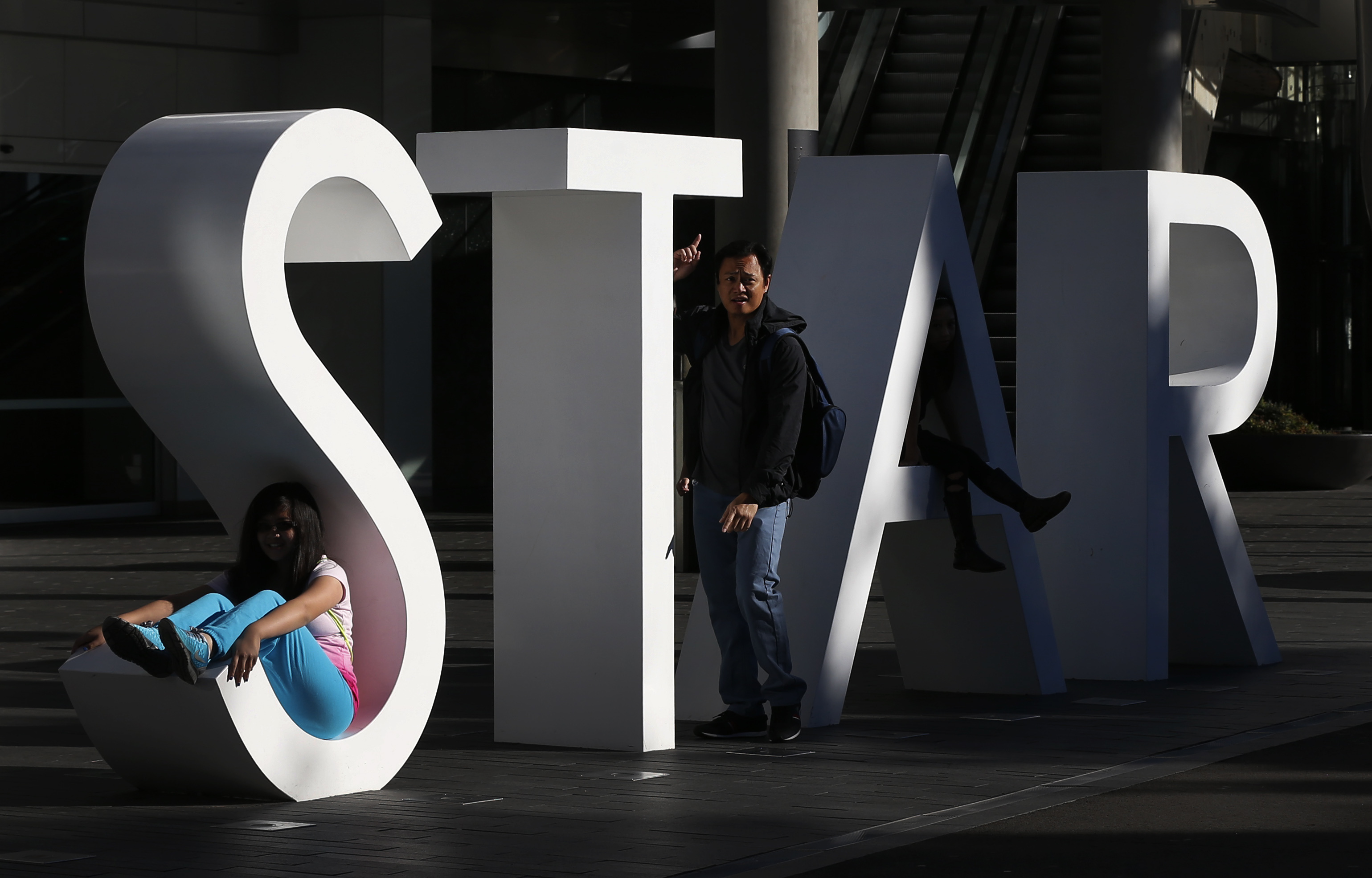 Tourist poses for pictures at the main sign of The Star Casino, owned by Echo Entertainment, at Pyrmont Bay in Sydney