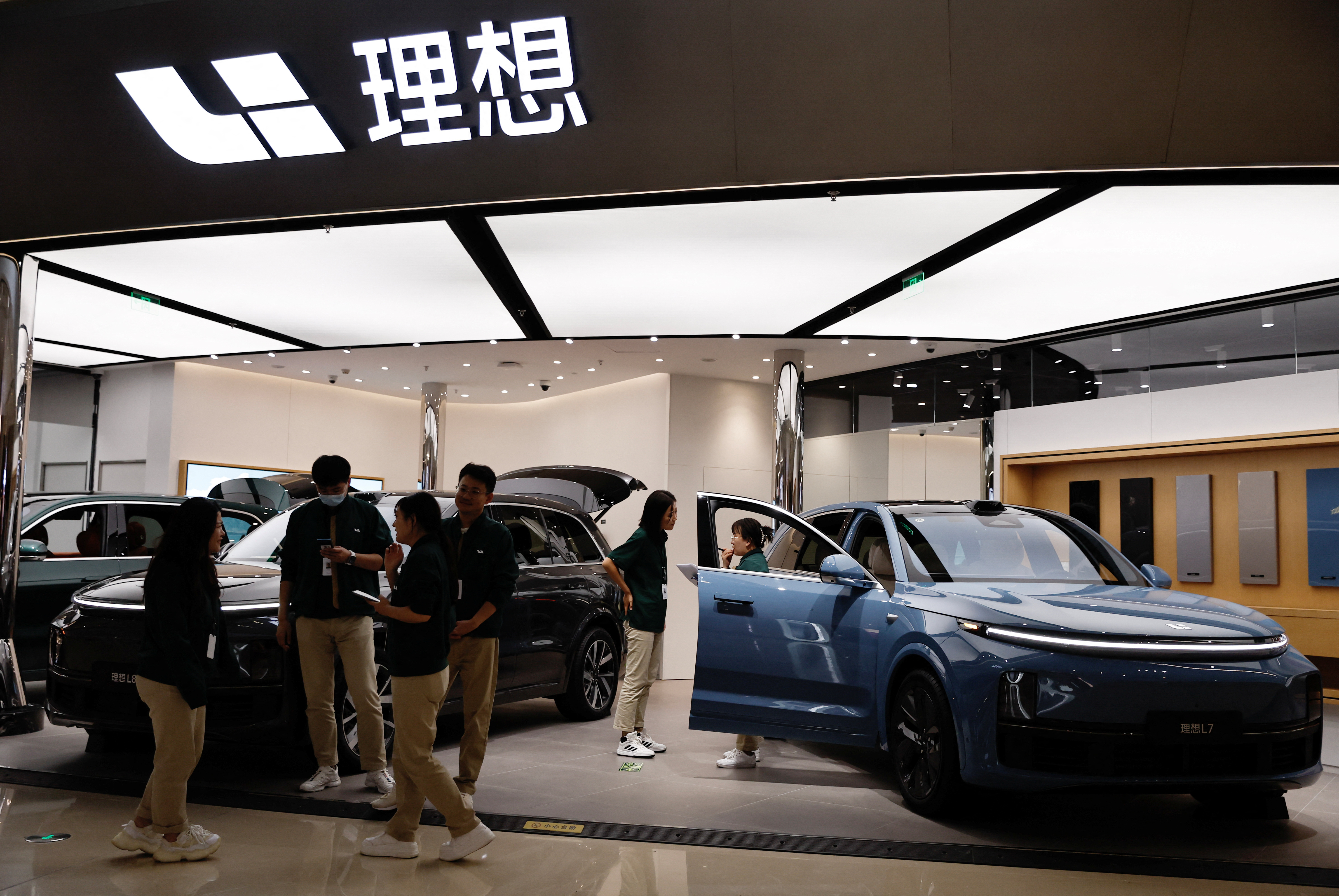 Staff members stand at the booth of Chinese electric vehicle (EV) maker Li Auto, at a shopping mall in Beijing