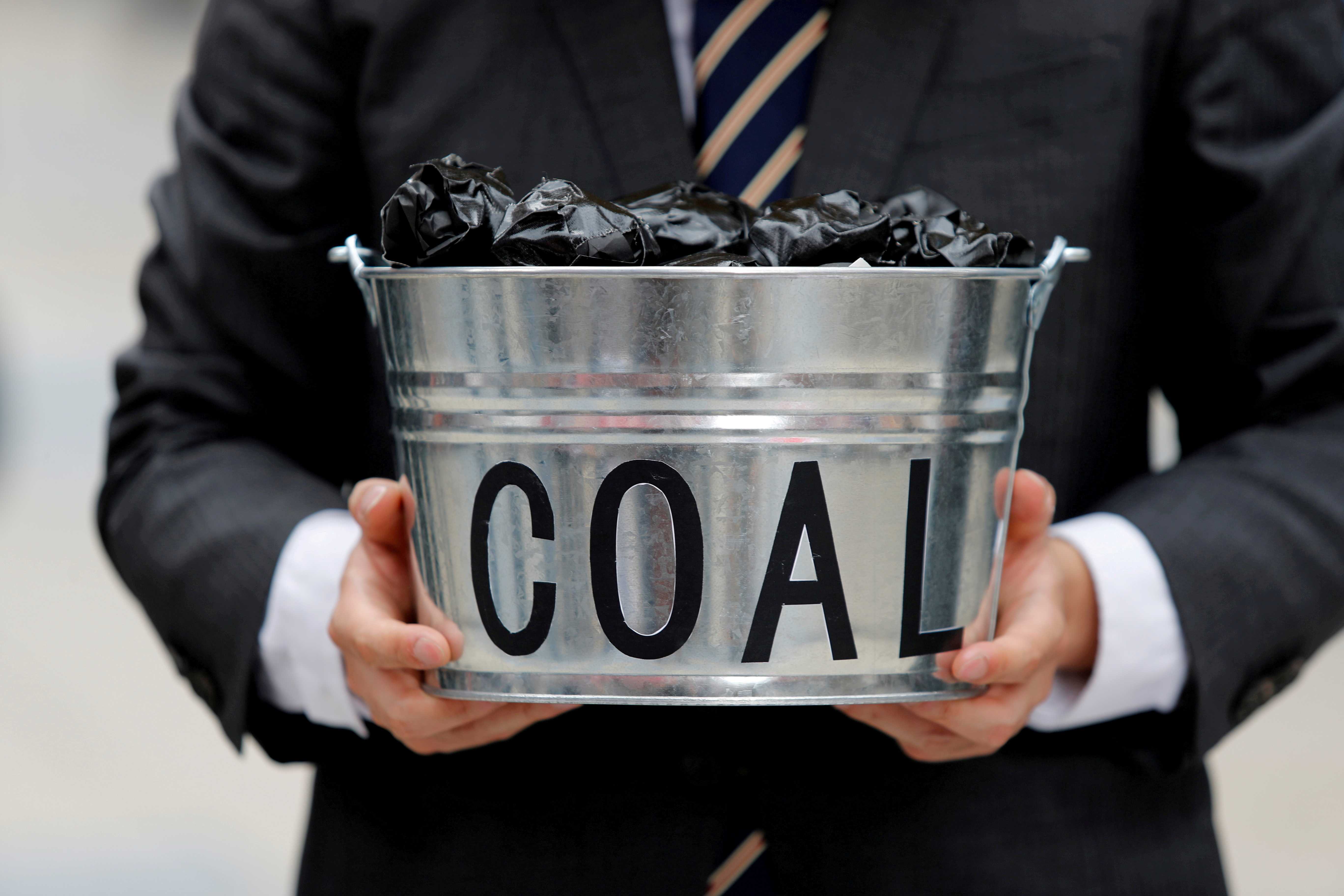 A protester holds a bucket of coal during a demonstration demanding Japan to stop supporting coal at home and overseas, at the G20 Summit in Osaka, Japan, June 28, 2019. REUTERS/Jorge Silva