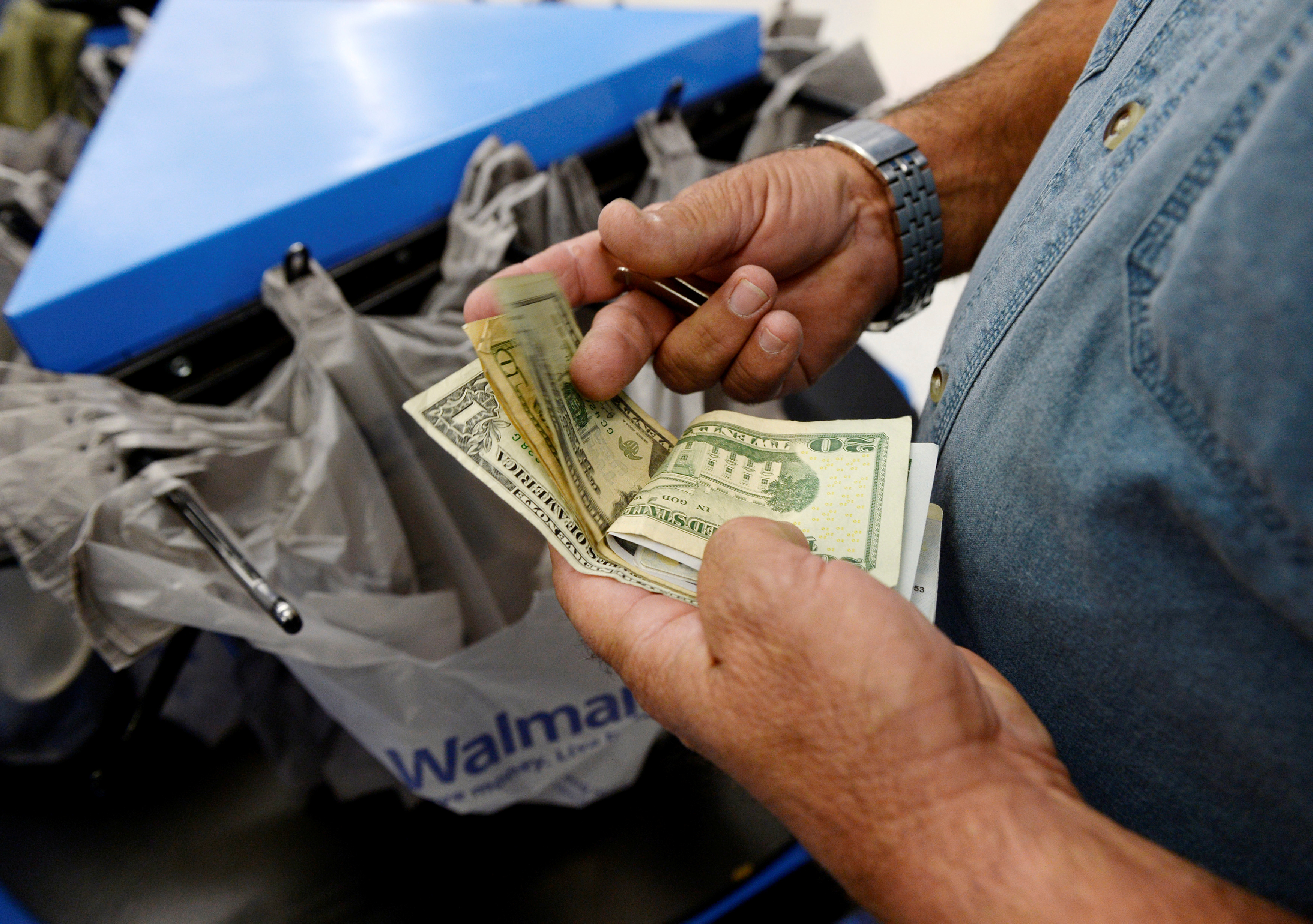 A customer counts his cash at the checkout lane of a Walmart store in the Porter Ranch section of Los Angeles