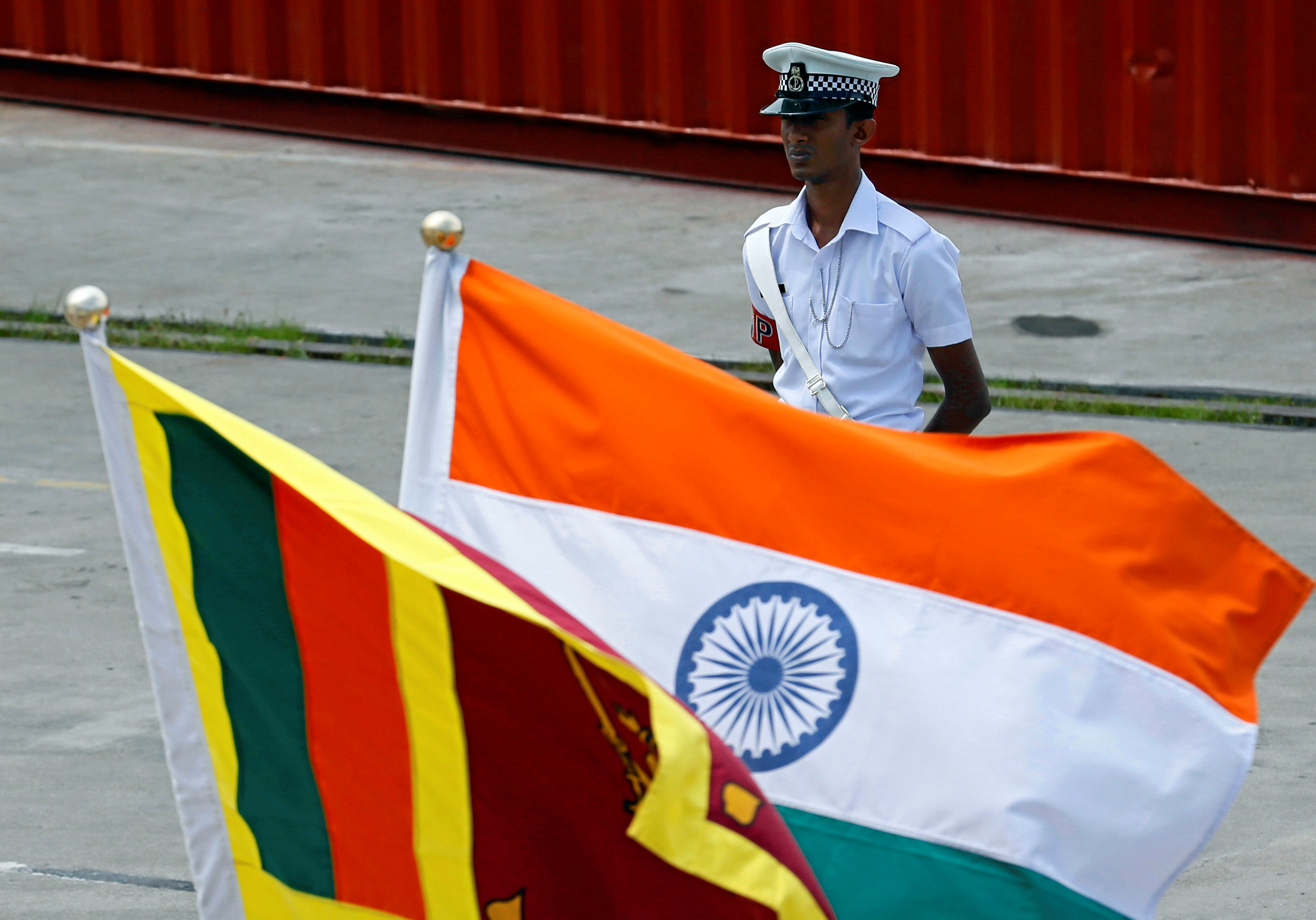A Navy officer stands in front of India's and Sri Lanka's national flags as Indian Coast Guard Ship Shoor is in the Colombo port during its visit in Colombo
