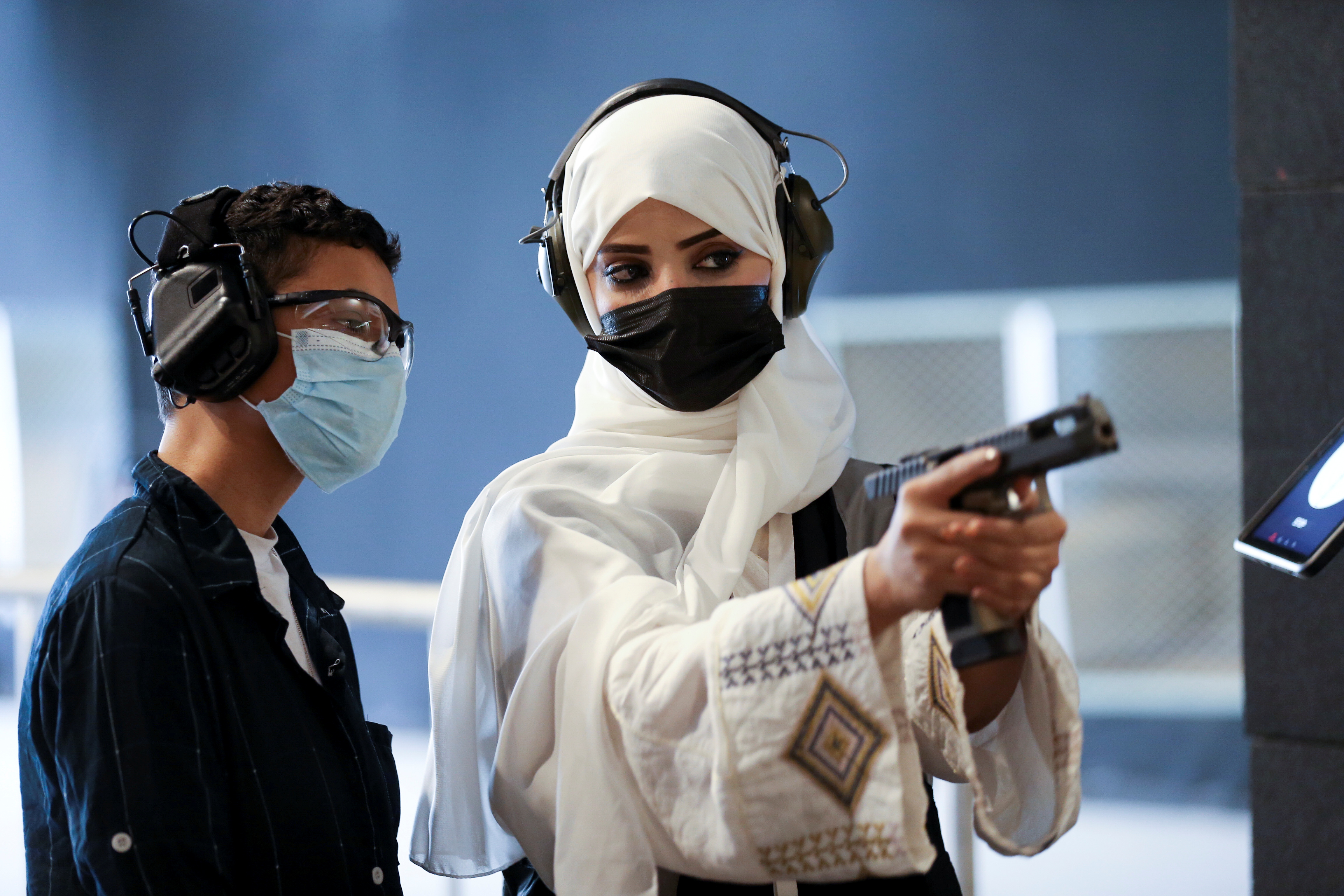 Saudi female firearm trainer, Mona Al Khurais, teaches a Saudi boy on safe usage of weapons at the Top-Gun shooting range in Riyadh, Saudi Arabia, October 28, 2021. REUTERS/Ahmed Yosri