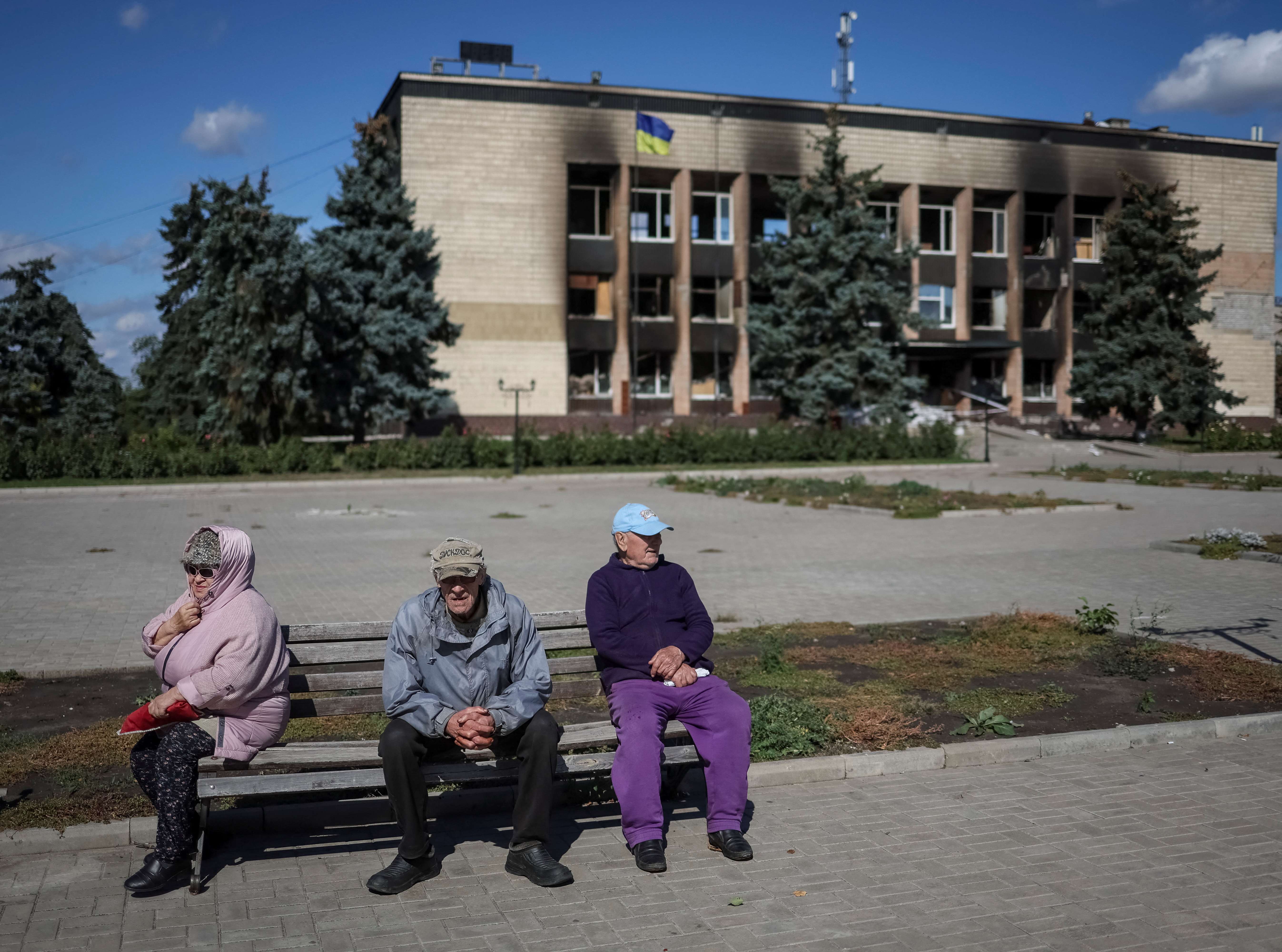Local residents sit on a bench in town of Izium