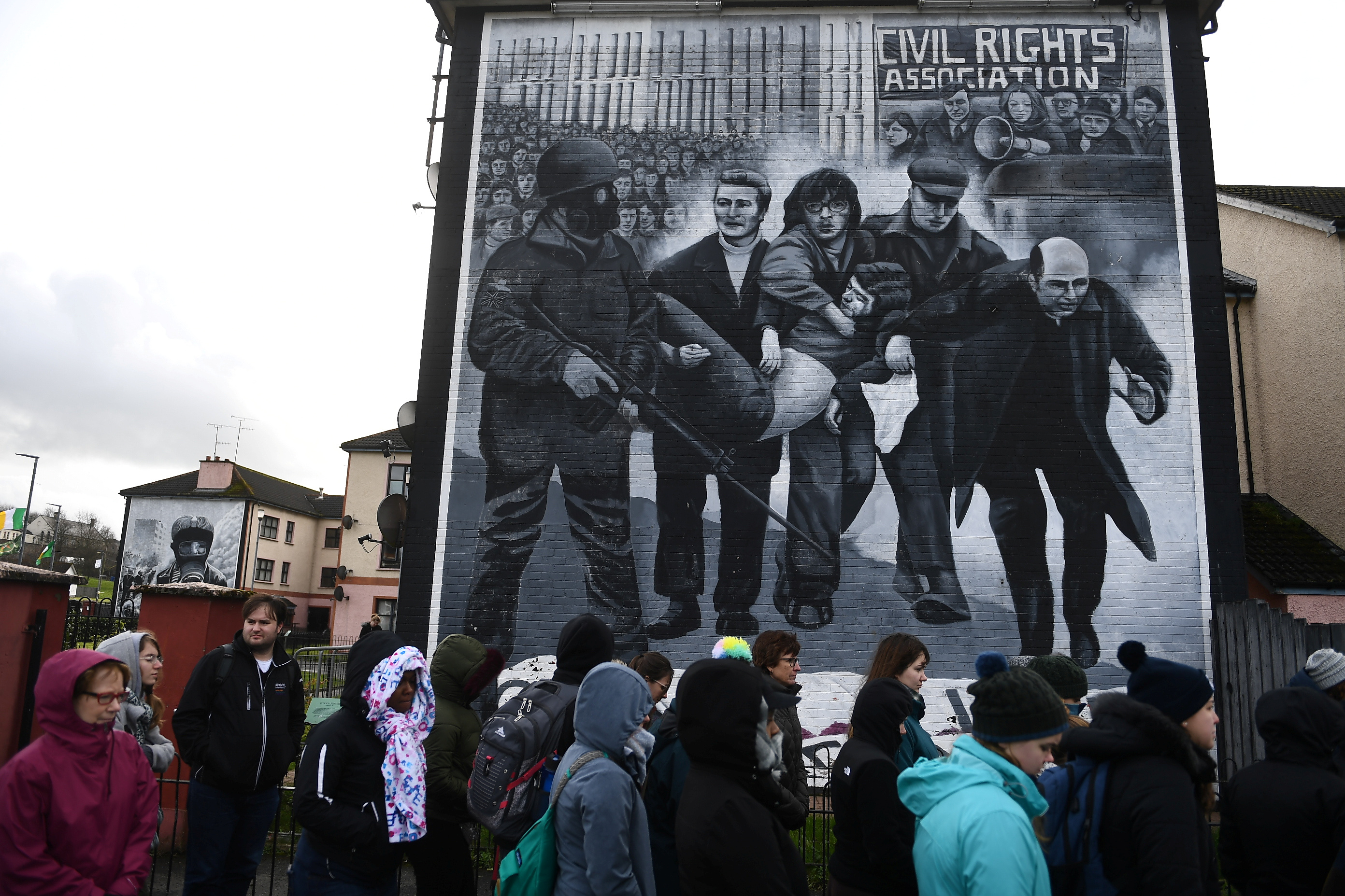 Tourists stand in front of a mural depicting the Bloody Sunday events, in Londonderry
