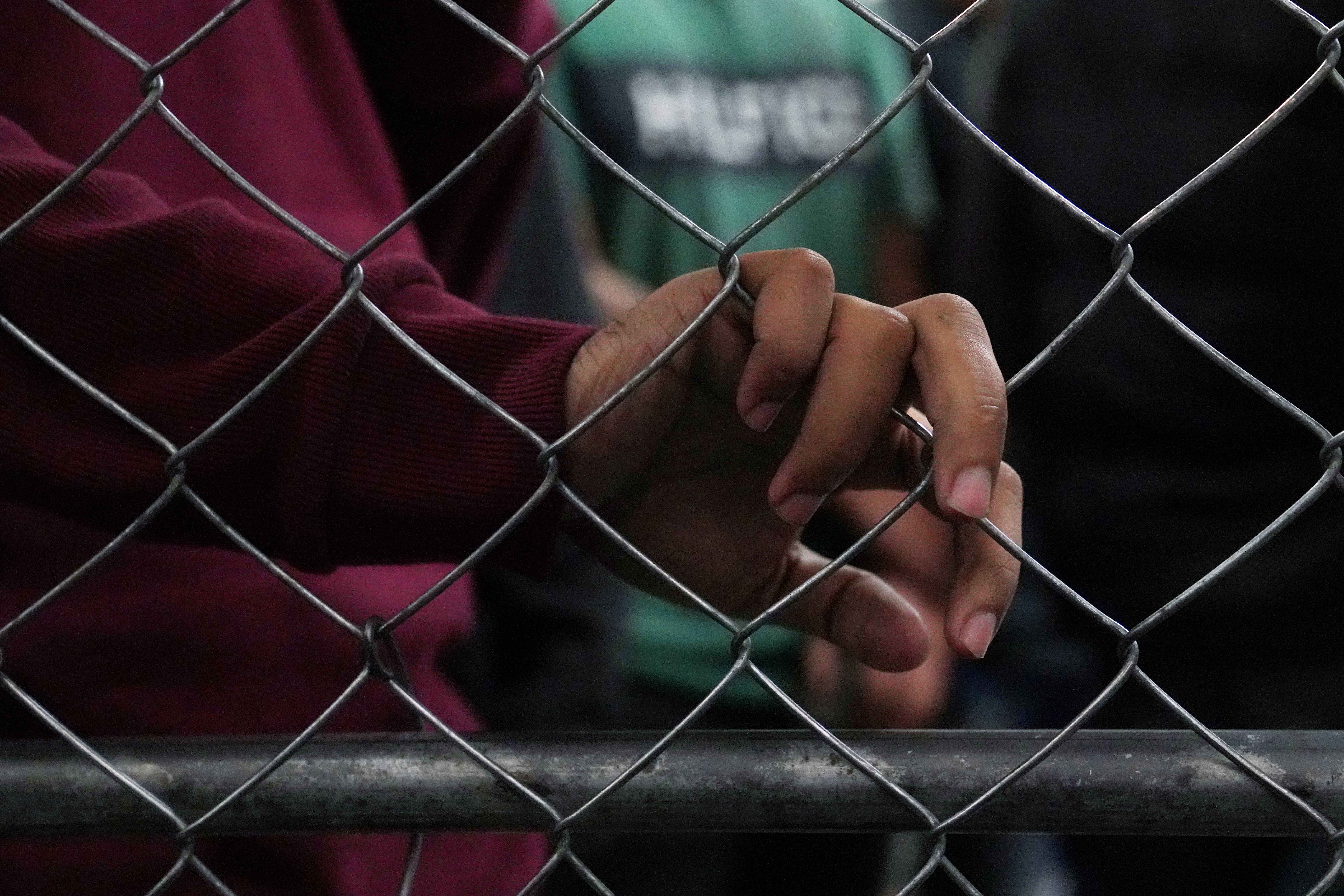 Single-adult male detainees wait along a fence inside a Border Patrol station in McAllen, Texas