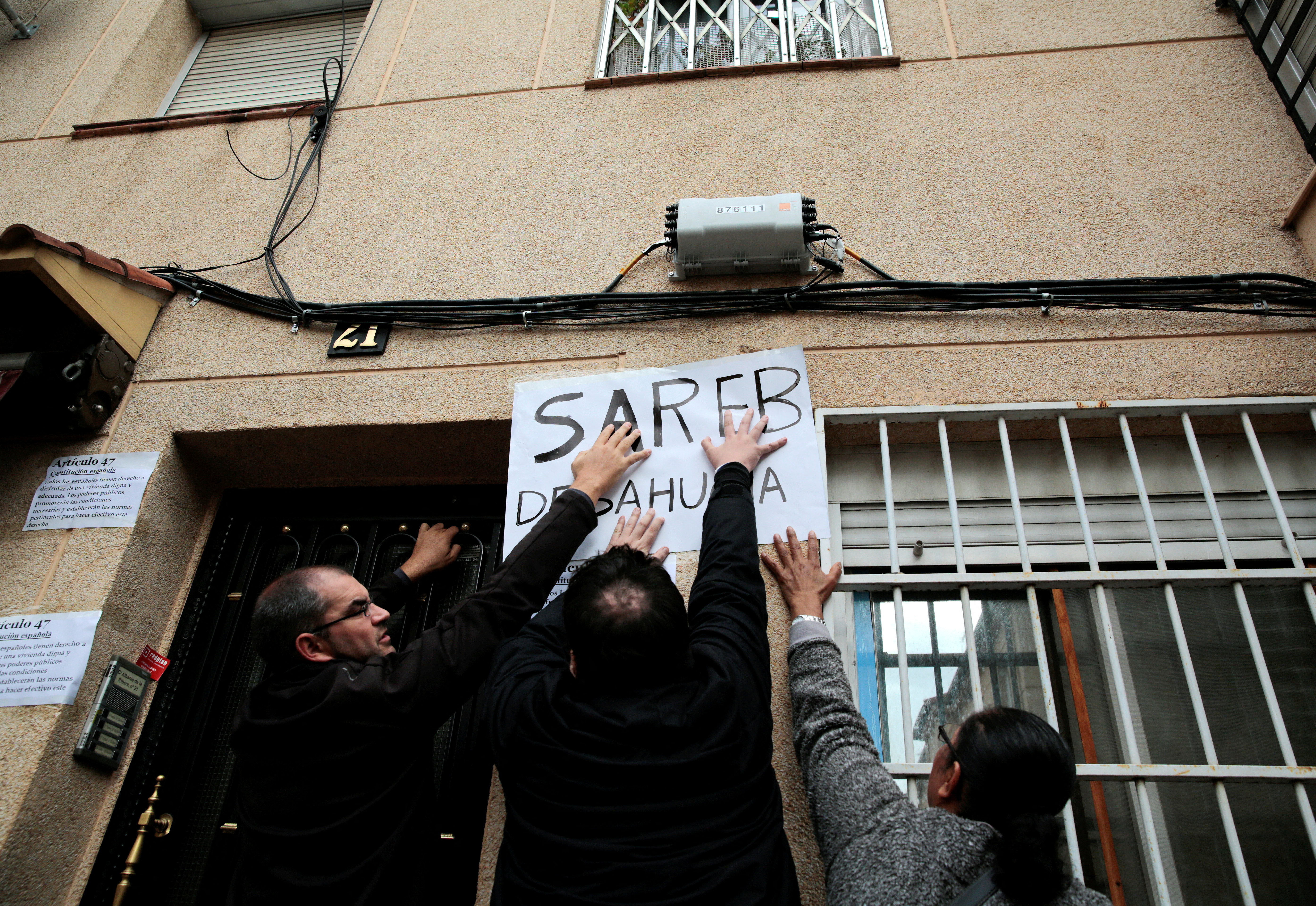 Anti-eviction activists stick a banner reading "Sareb evicts" against a wall as they wait for an eviction in Madrid