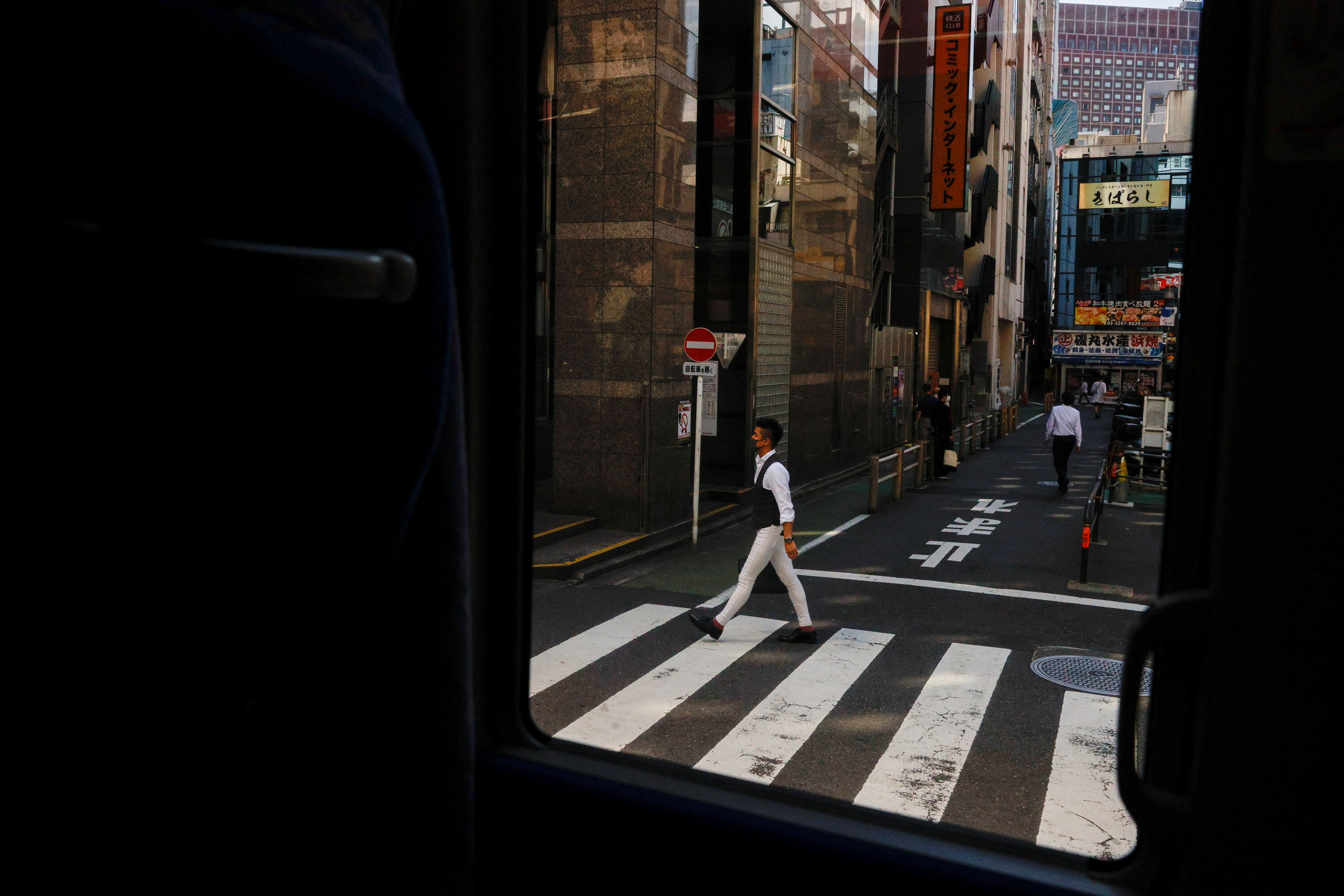 A man crosses a street ahead of the Tokyo 2020 Olympic Games that have been postponed due to the coronavirus disease (COVID-19) in Tokyo
