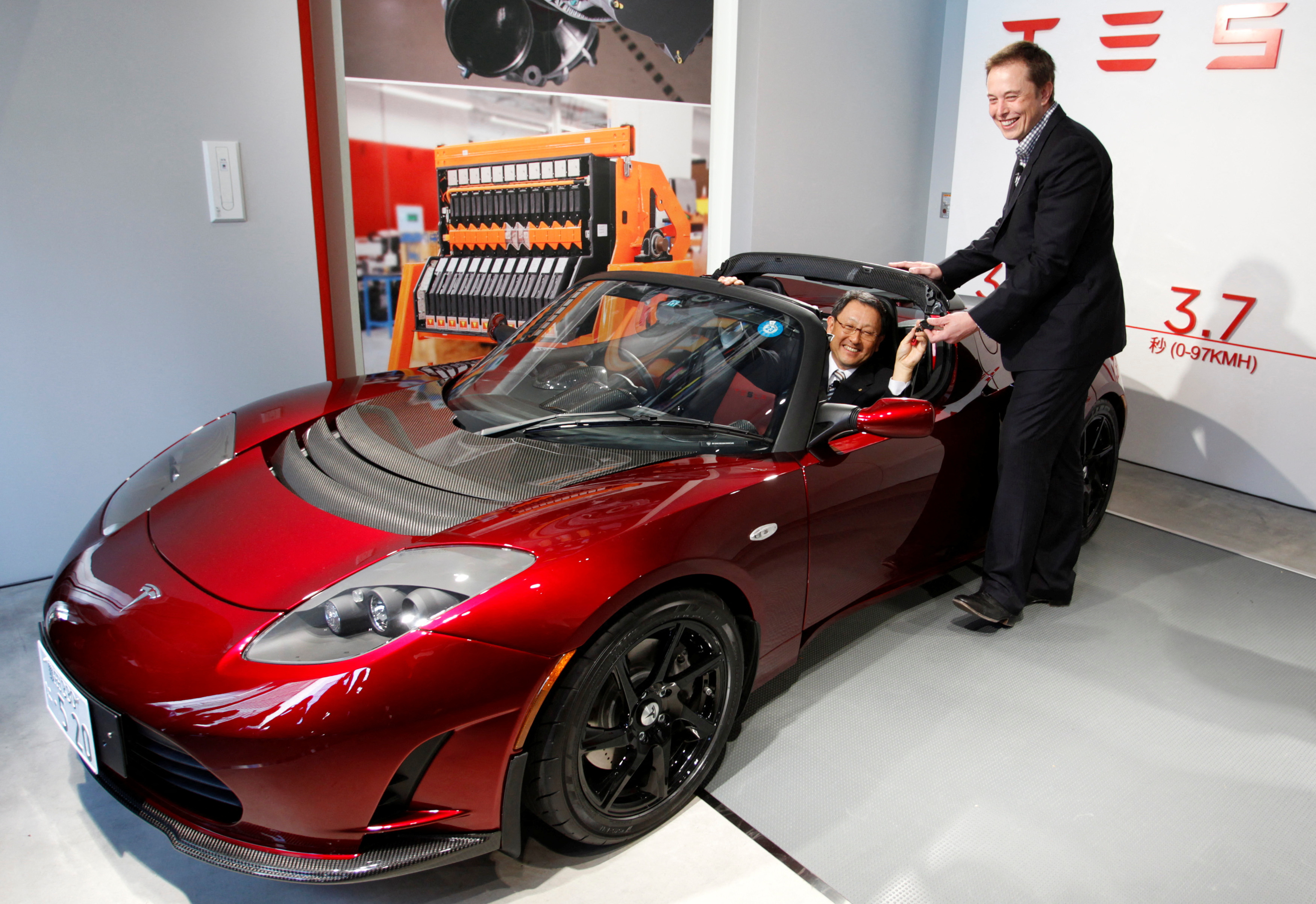 Toyota Motor Corp President Toyoda is presented with the keys to a Roadster electric car by Tesla Motor Inc CEO Musk at a news conference in Tokyo