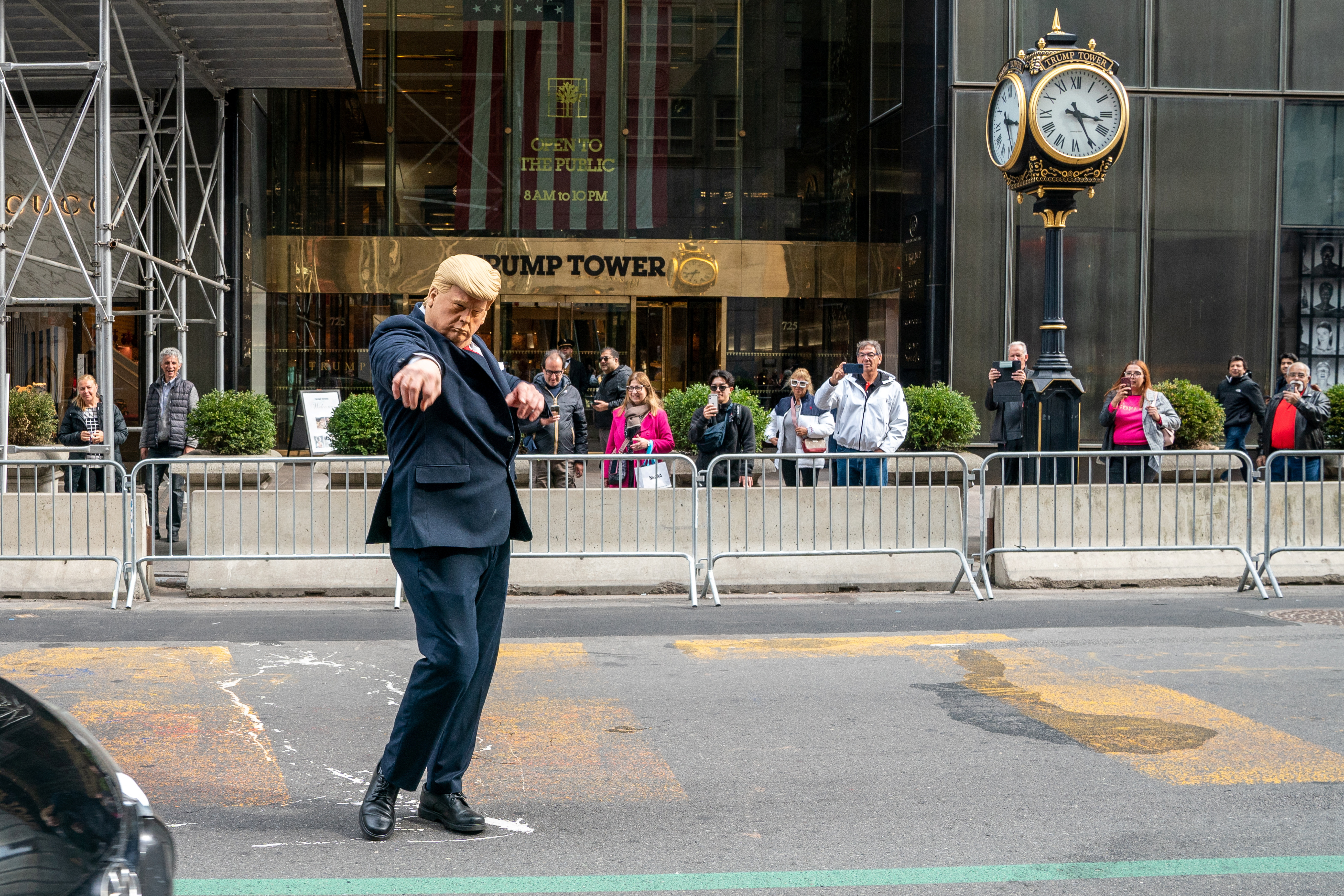 A person wearing a mask depicting former U.S. President Trump directs traffic outside of Trump Tower, in New York