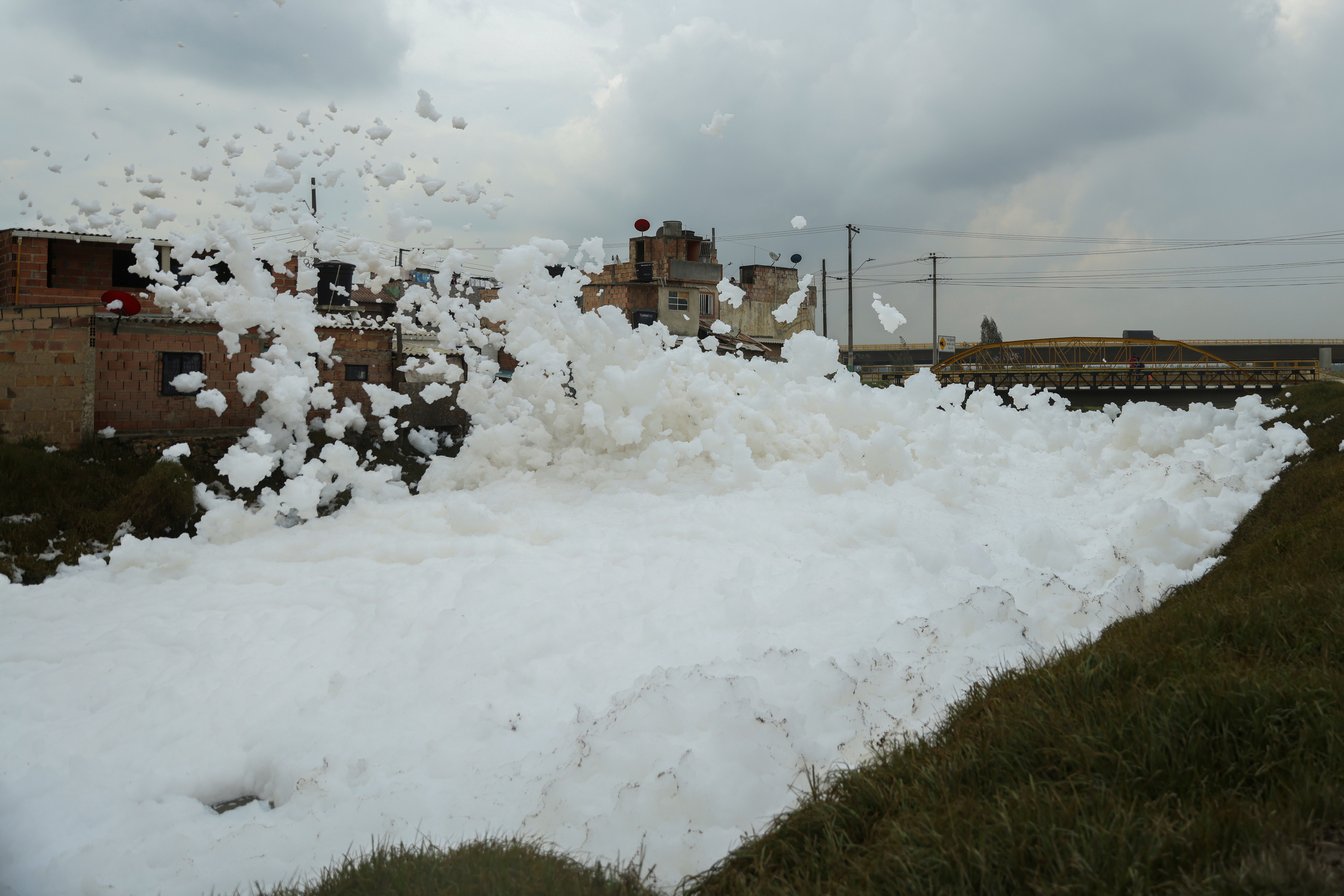Pollutant foam generated by a river full of waste is blown by the wind next to houses, in Mosquera
